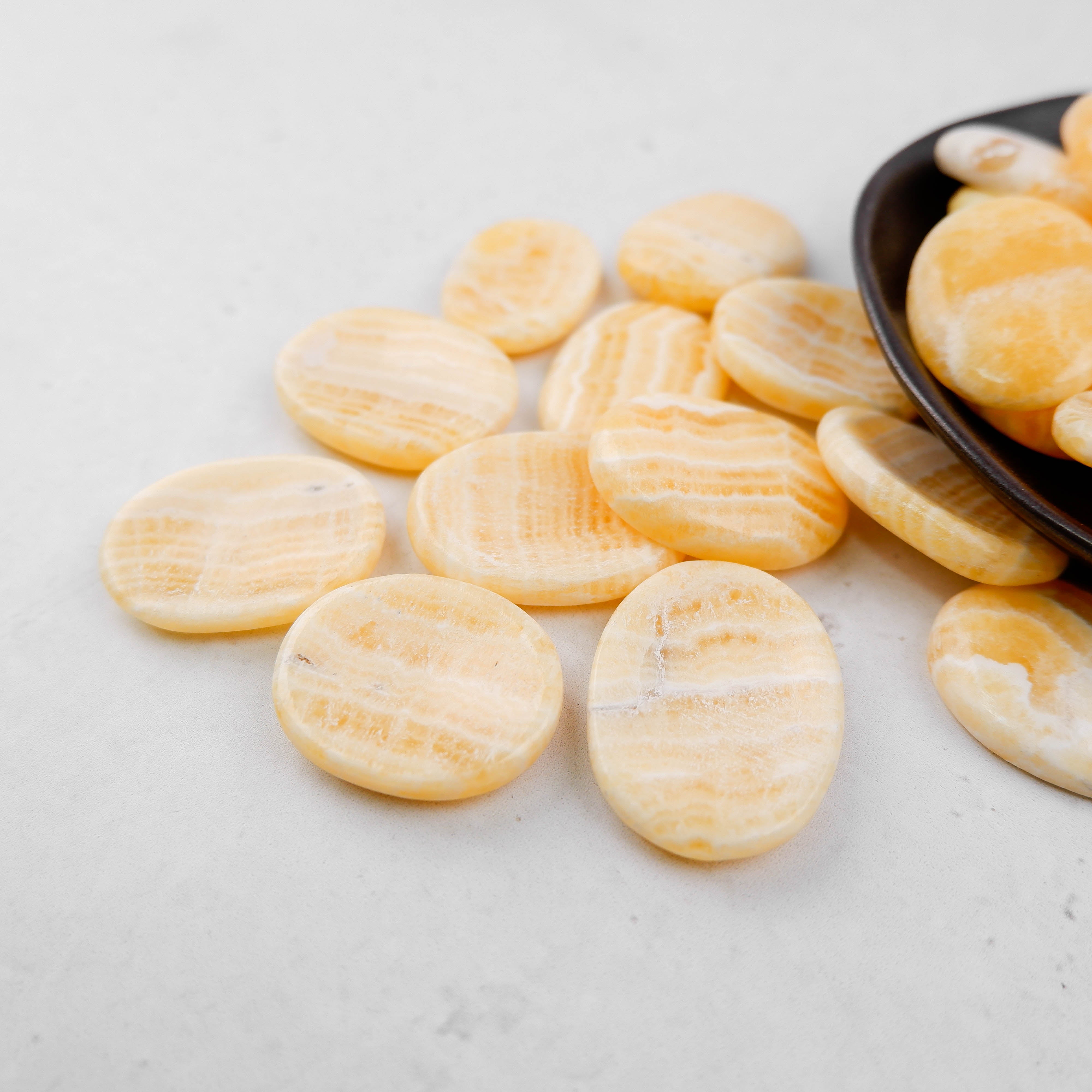 Orange banded calcite worry stone from Noctis Studio, smooth polished gemstone with vibrant orange and white banding.