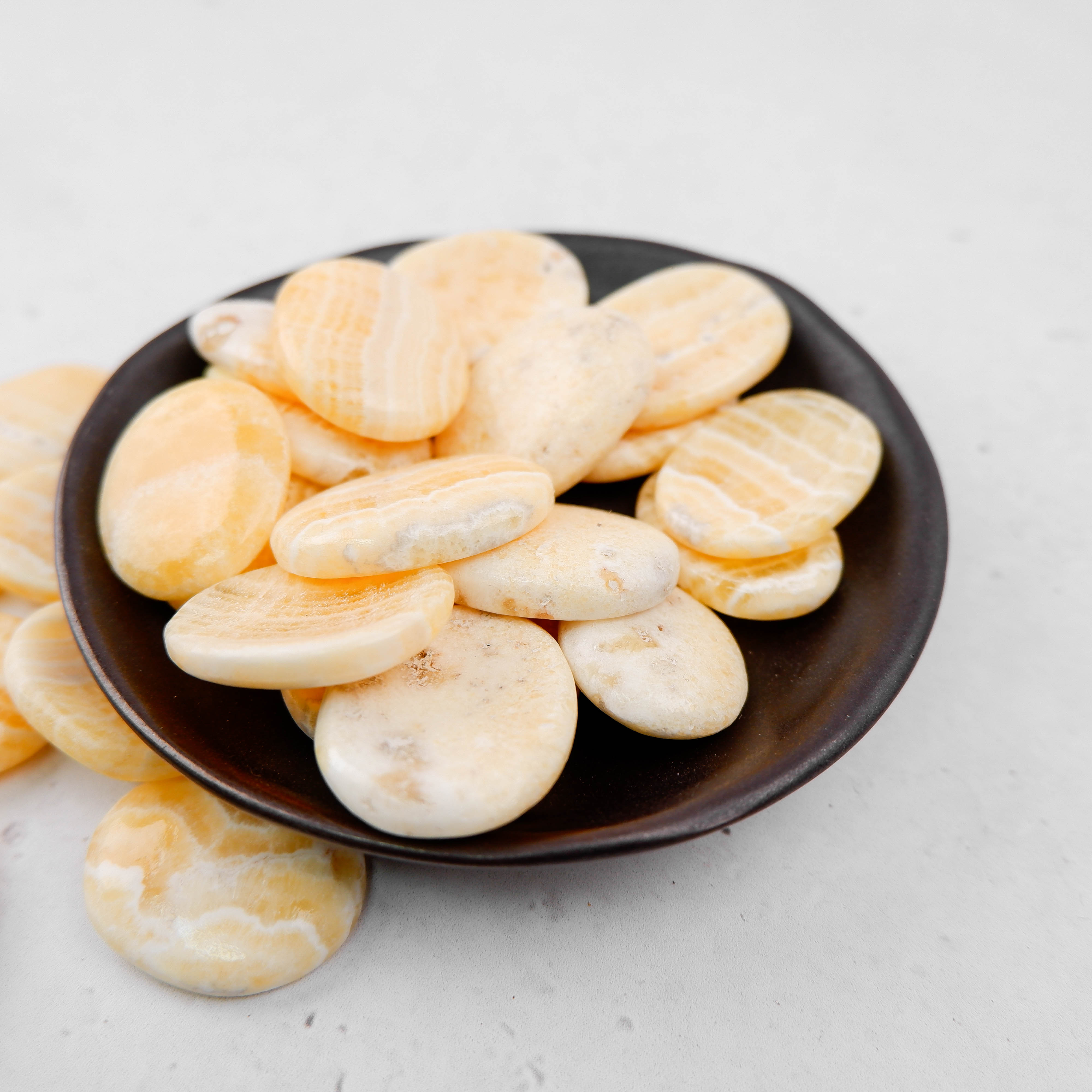 Orange banded calcite worry stone from Noctis Studio, smooth polished gemstone with vibrant orange and white banding.