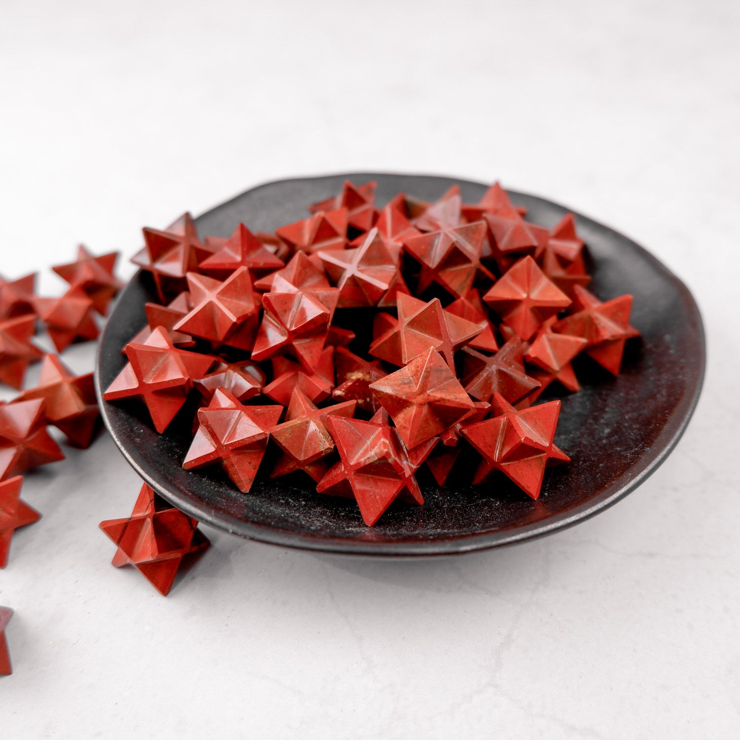 Red Jasper star from Noctis Studio, polished gemstone with vibrant red color and star-shaped carving, displayed on a neutral background.