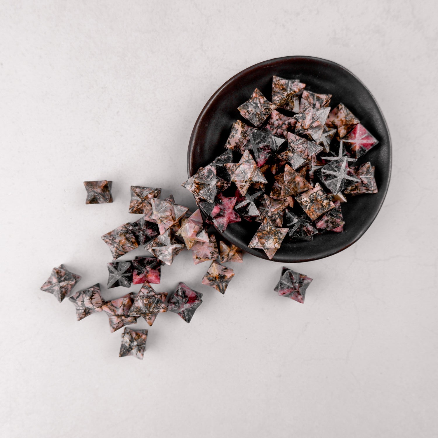 Rhodonite star-shaped gemstone from Noctis Studio, featuring a polished pink and black patterned surface with a smooth finish.