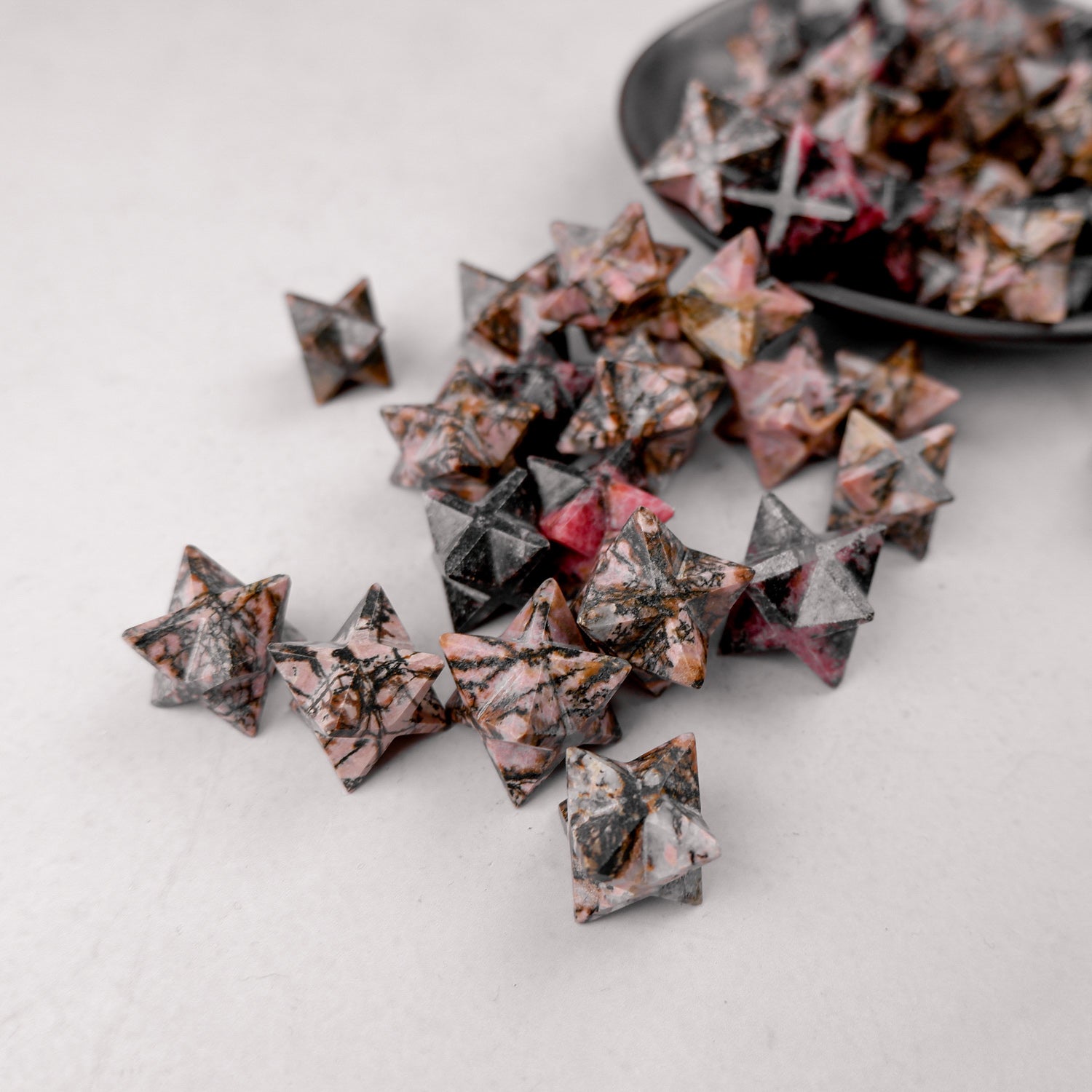 Rhodonite star-shaped crystal sculpture by Noctis Studio, featuring a polished pink and black stone with star form details.