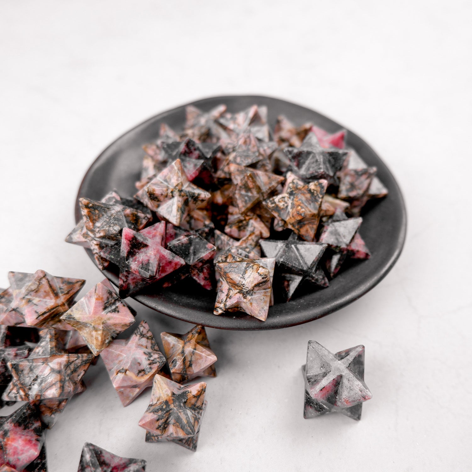 Rhodonite star-shaped gemstone sculpture by Noctis Studio, showcasing vibrant pink and black mineral patterns.
