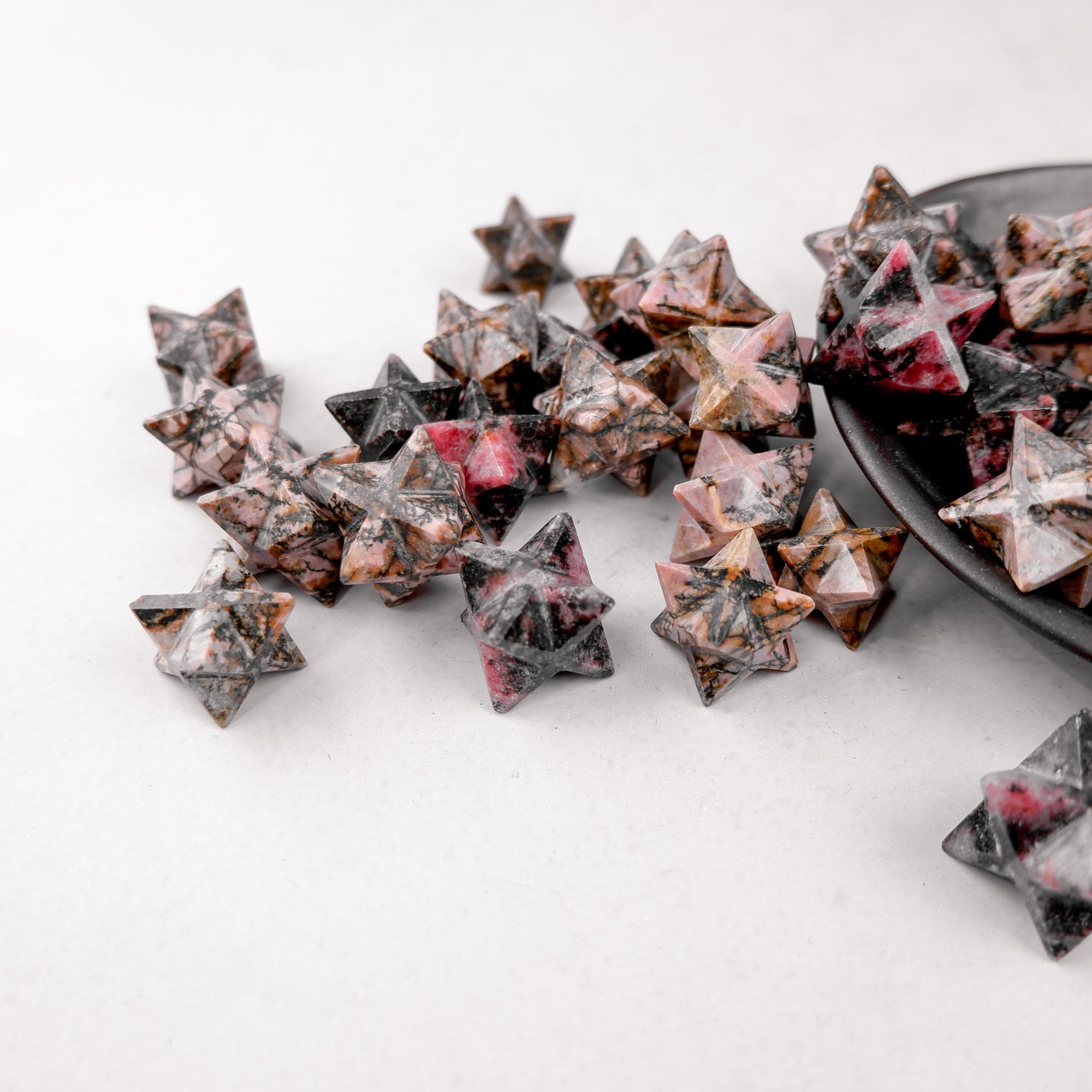 Rhodonite star-shaped gemstone from Noctis Studio with vibrant pink and black marbling, polished and smooth surface.