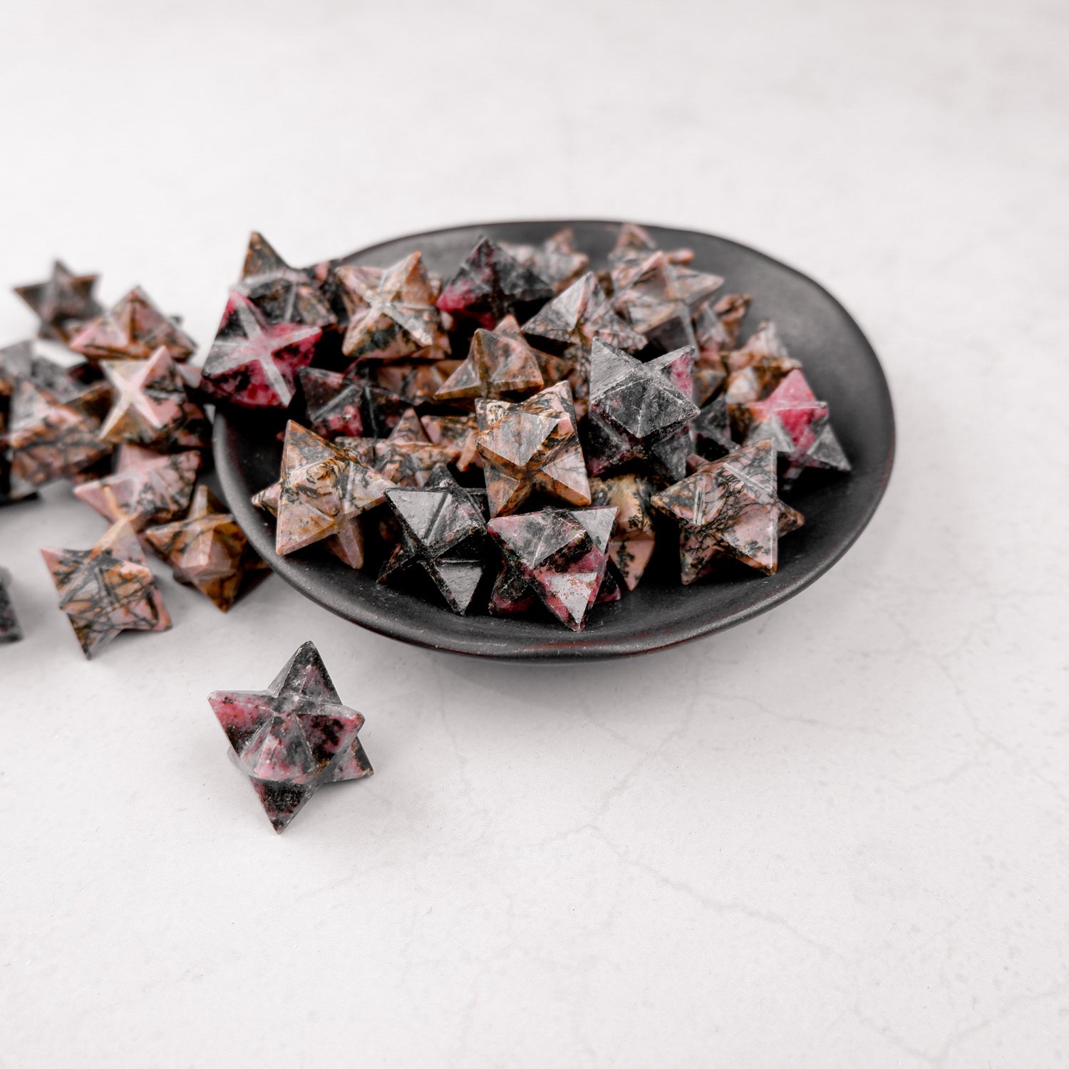Rhodonite star gemstone from Noctis Studio showcasing a polished pink and black marbled star shape.