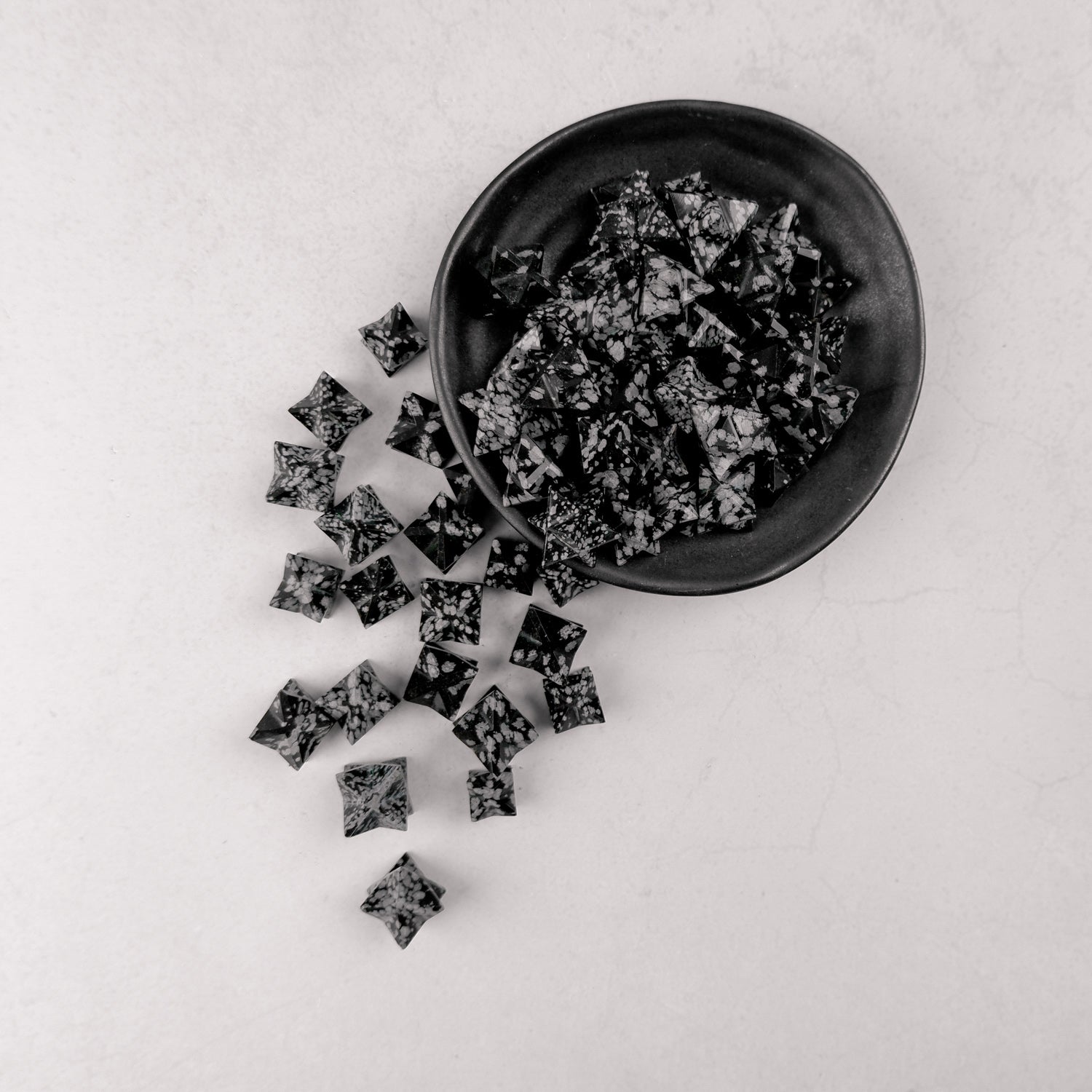 Snowflake Obsidian star sculpture by Noctis Studio, showcasing a smooth black stone with white snowflake patterns and a star shape.