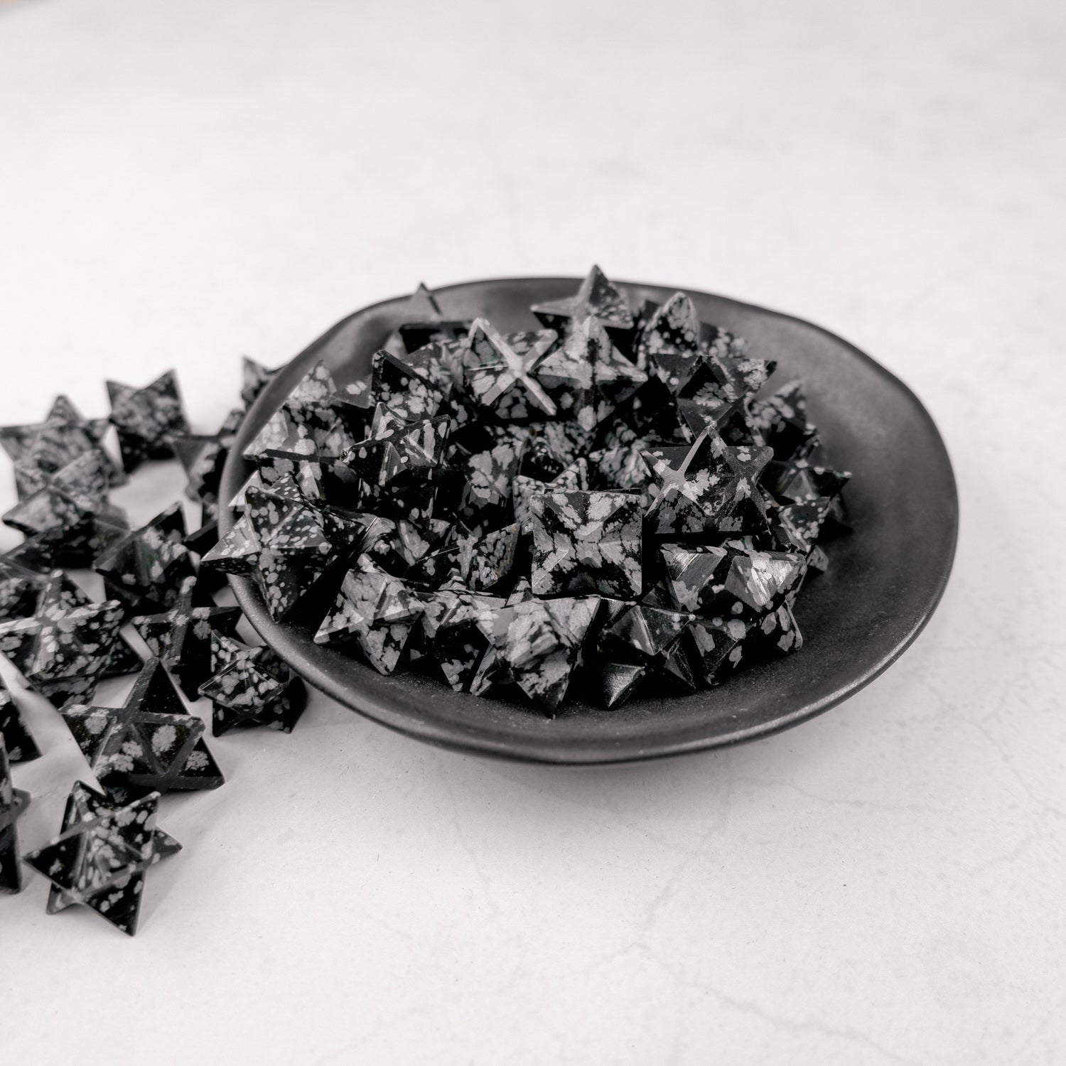 Star-shaped Snowflake Obsidian gemstone from Noctis Studio, showcasing black stone with white snowflake patterns.