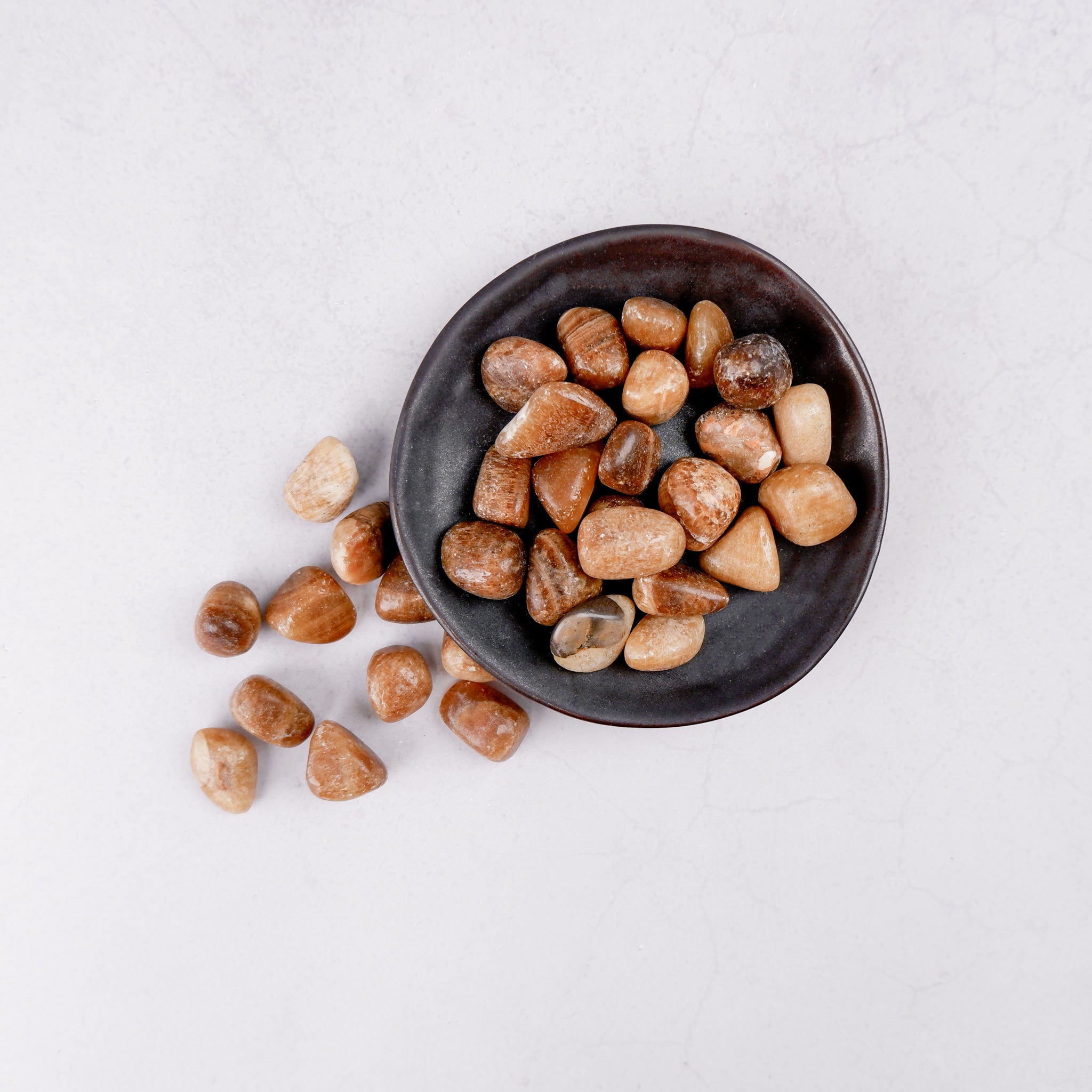 Noctis Studio Aragonite tumble stone showing a smooth, rounded mineral with natural beige and white banding on a neutral background.