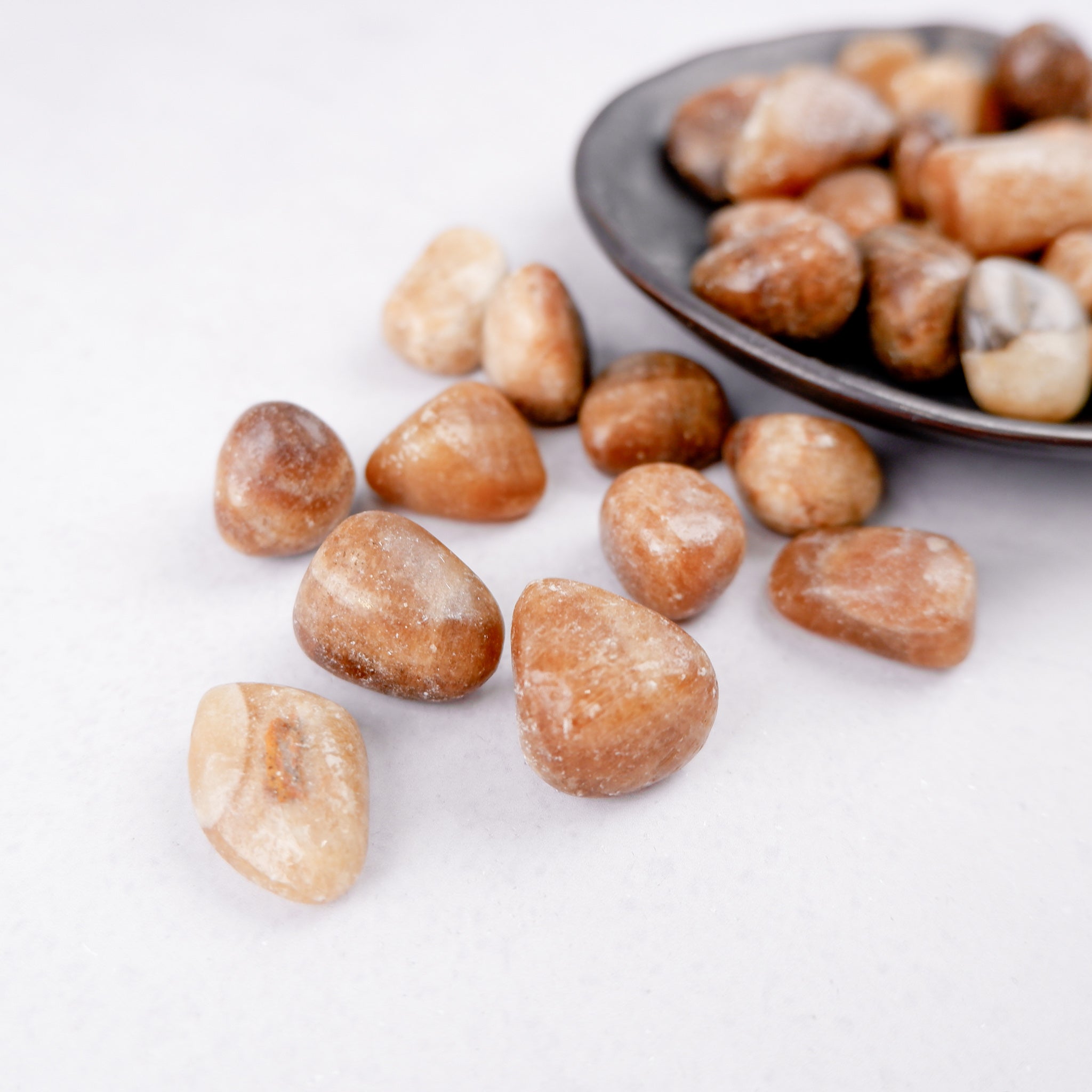 Aragonite tumble stone from Noctis Studio showcasing a polished, natural mineral with earthy brown and white tones.