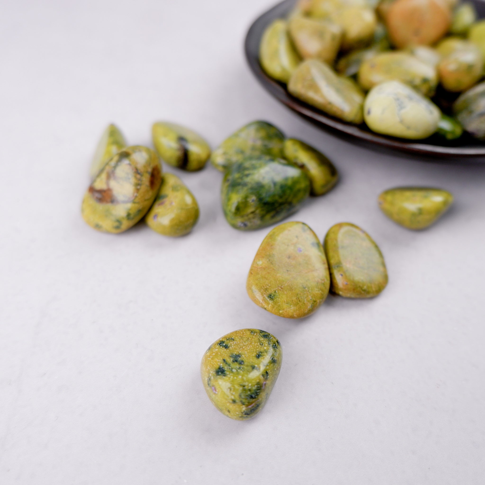 Noctis Studio Atlantisite tumble stone showing vibrant green and blue patterns on polished mineral surface.