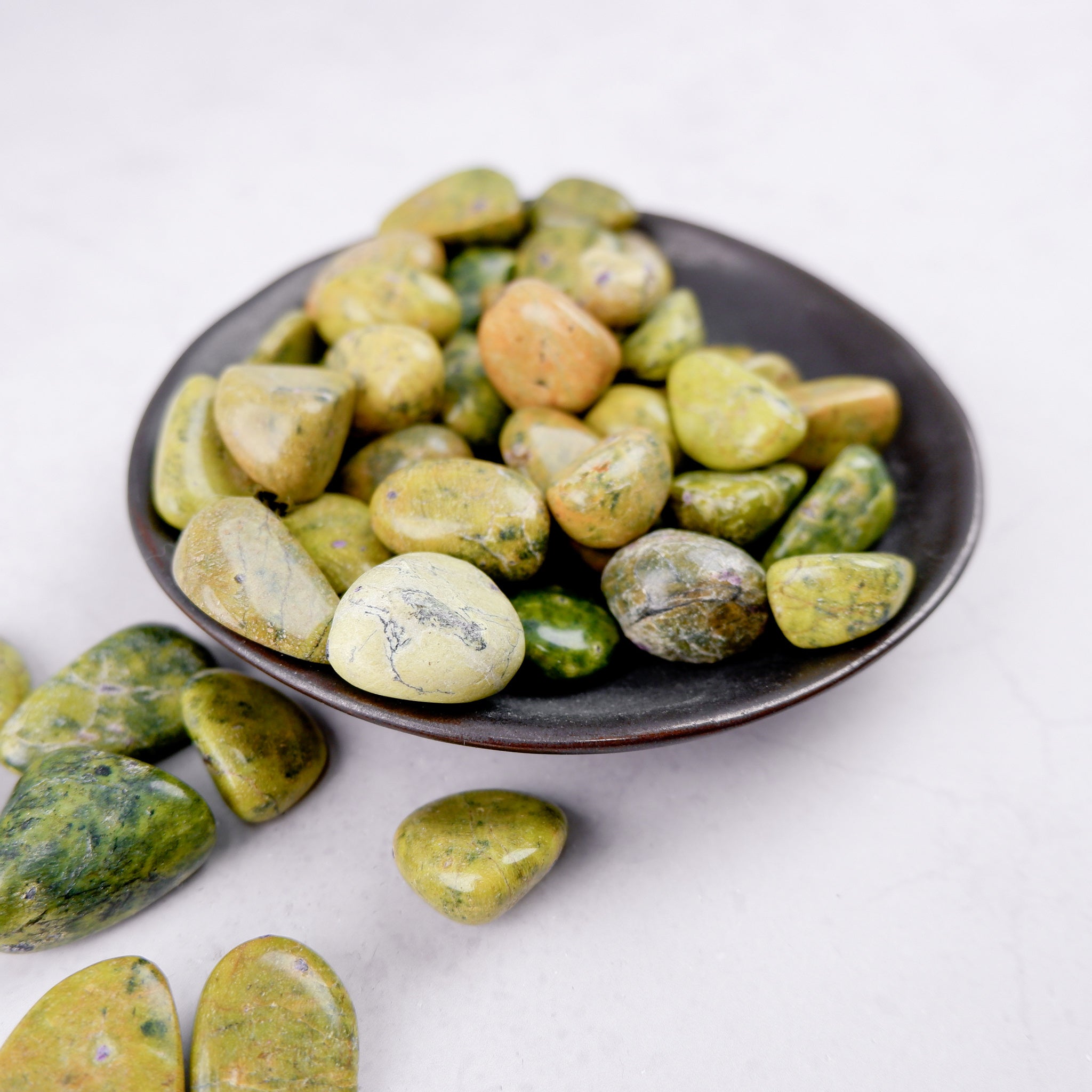 Noctis Studio Atlantisite tumble stone showing vibrant green and blue mineral patterns on a polished surface.