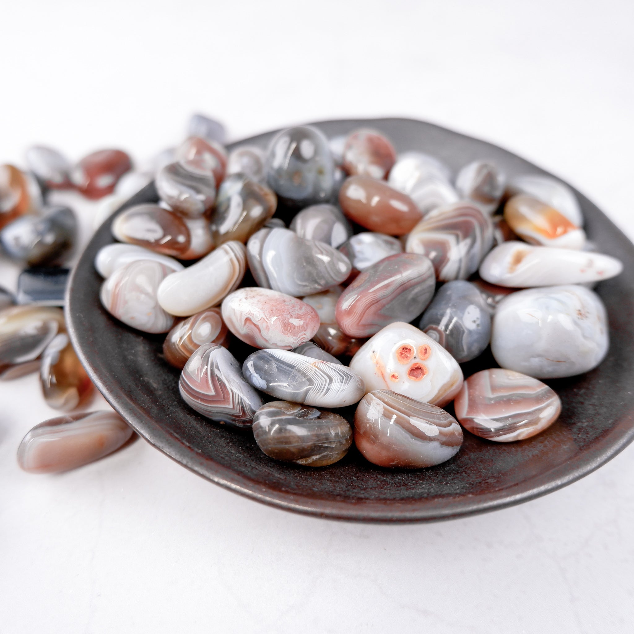 Botswana Agate tumble stone from Noctis Studio, showing polished, smooth, and colorful banded gemstone with natural patterns.