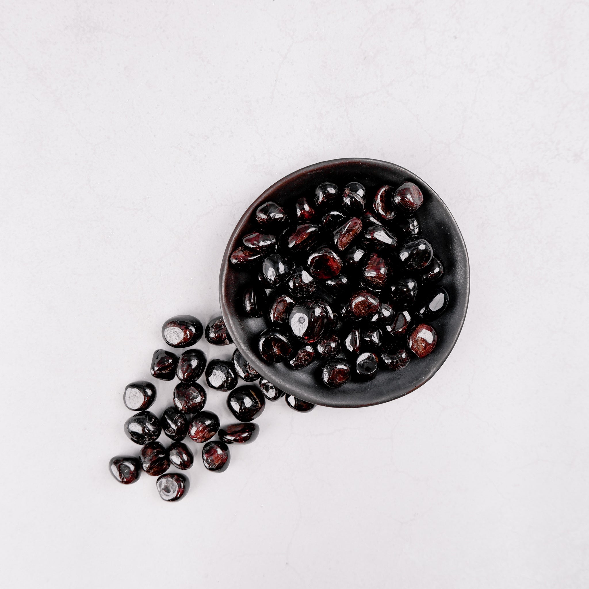 Garnet tumble stone from Noctis Studio, smooth polished gemstone with deep red color, displayed on a neutral background.