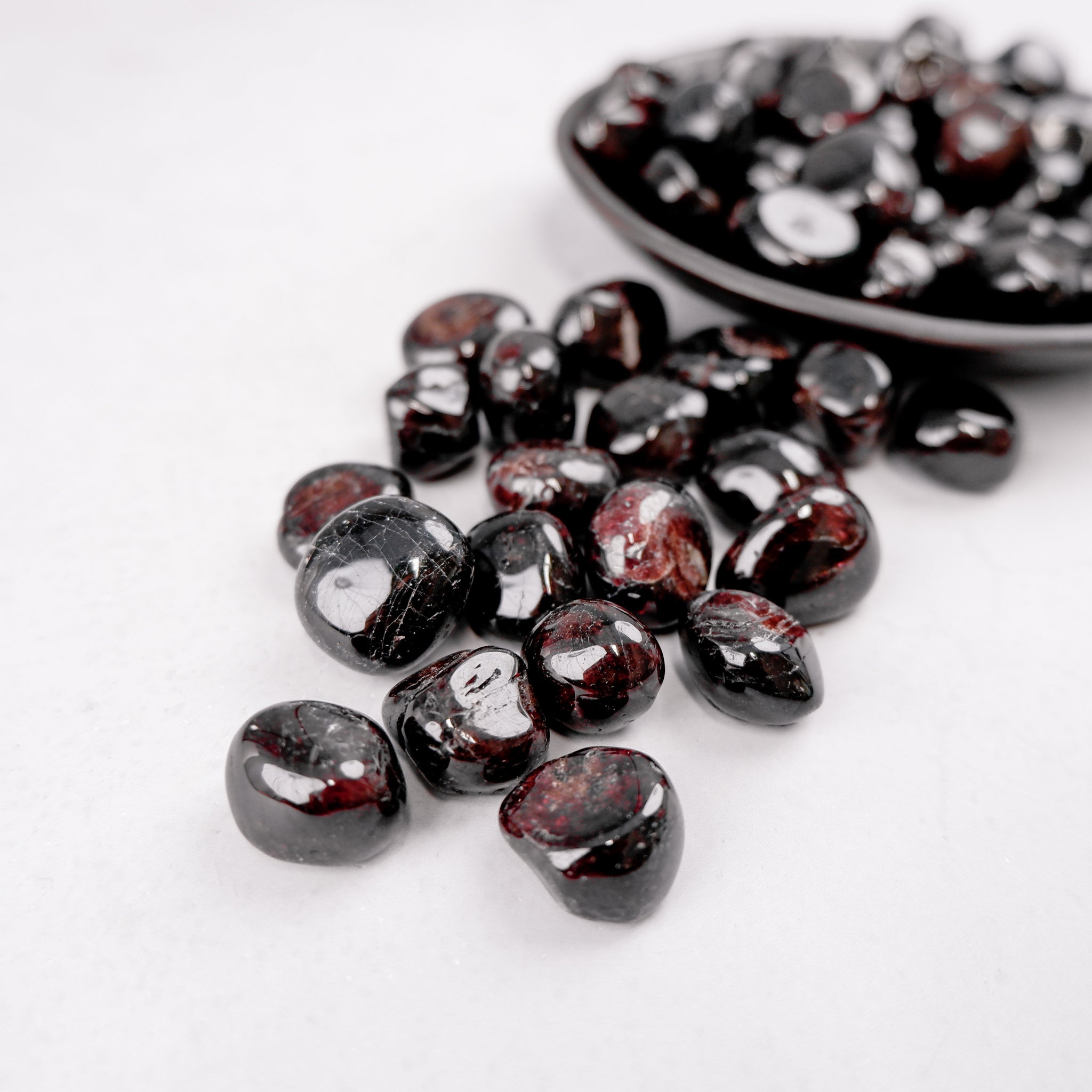 Garnet tumble stone from Noctis Studio, polished mineral gemstone with deep red color and smooth surface.