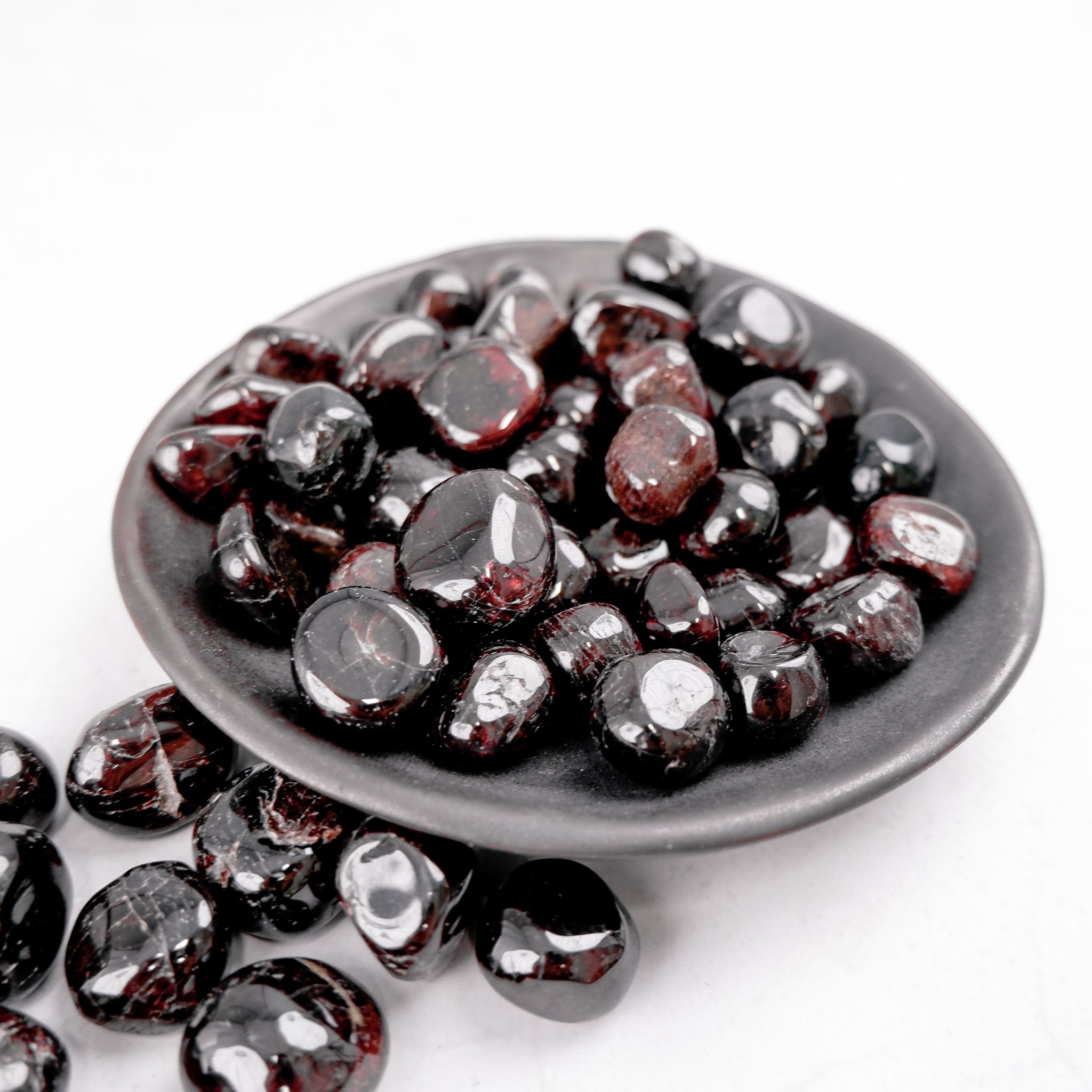Garnet tumble stone from Noctis Studio, smooth polished gemstone with deep red color and natural crystalline texture.