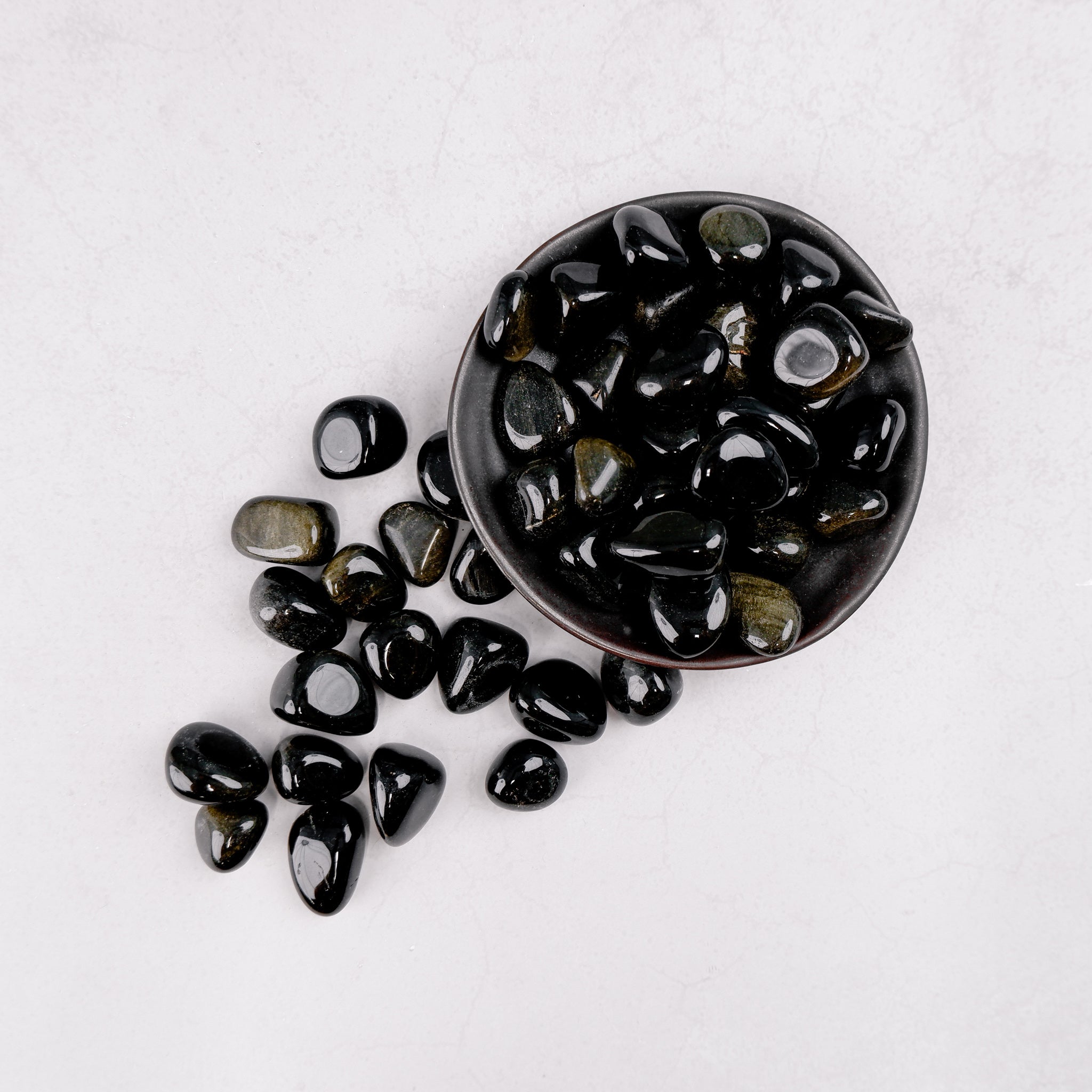 Golden Sheen Obsidian tumble stone from Noctis Studio showing smooth, polished dark stone with golden iridescent sheen.