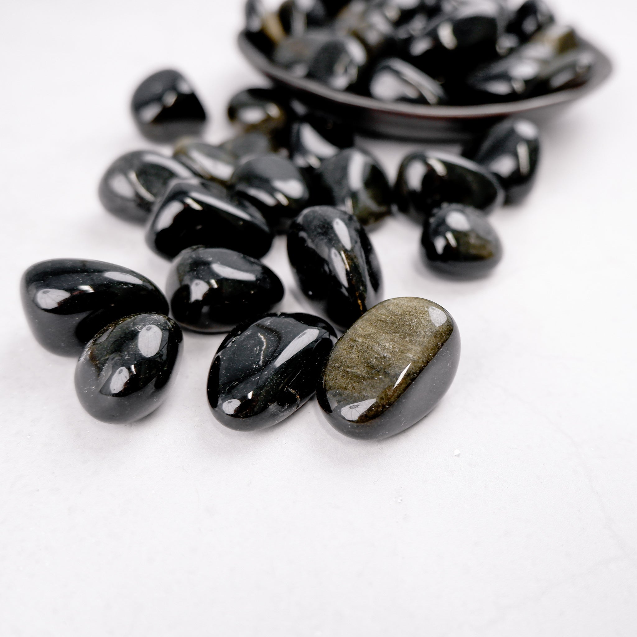Golden Sheen Obsidian tumble stone from Noctis Studio showing its polished, reflective surface and rich golden coloration.