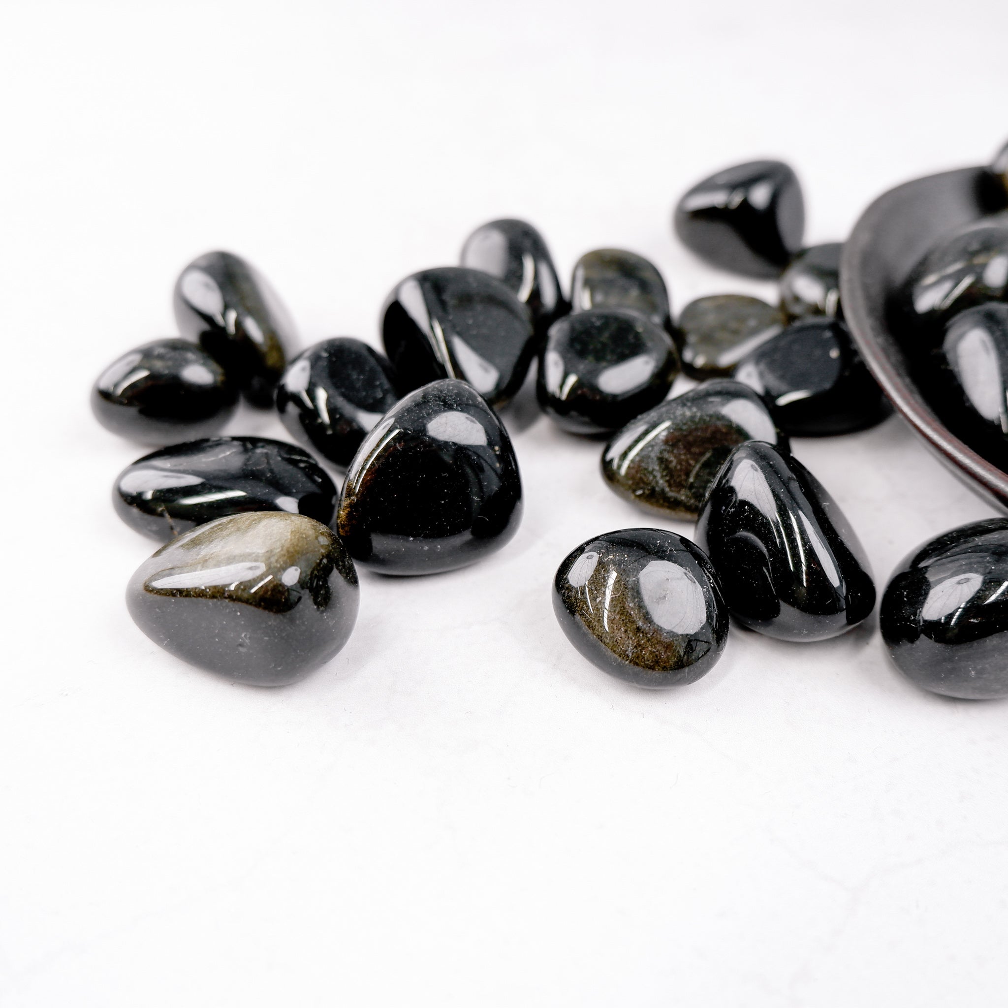 Golden Sheen Obsidian tumble stone from Noctis Studio showcasing its polished, shiny surface and rich golden hues.