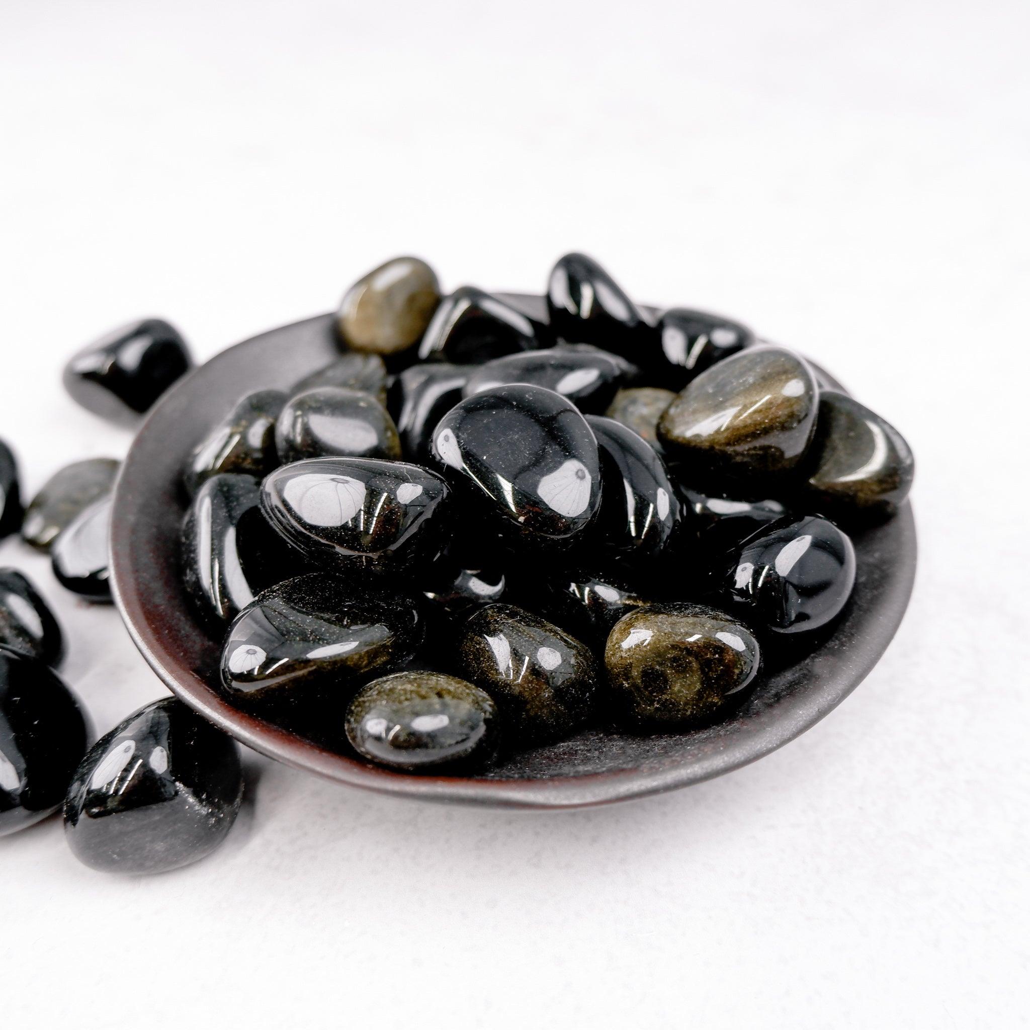 Golden Sheen Obsidian tumble stone from Noctis Studio, showcasing smooth, polished black volcanic glass with golden iridescent sheen.