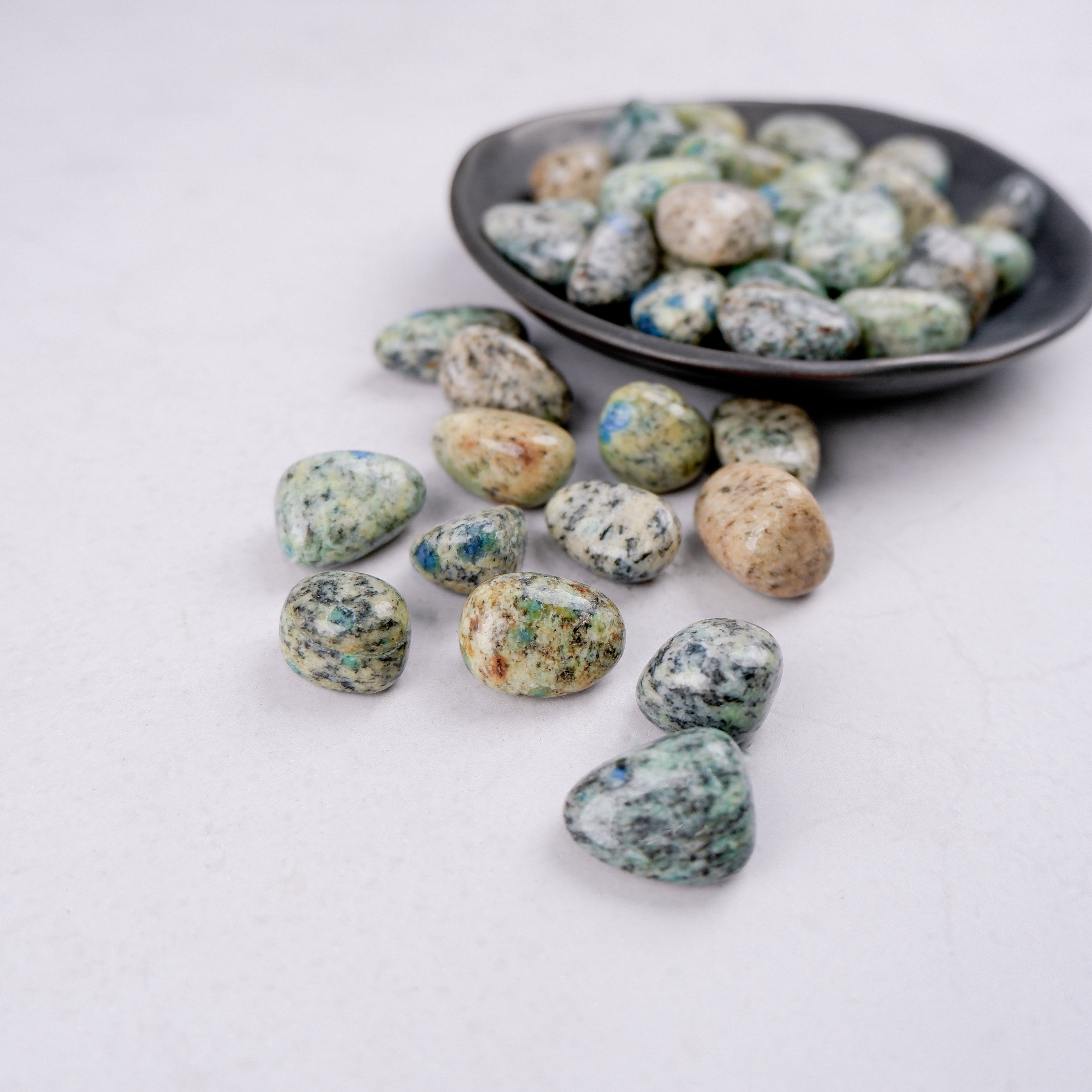 Noctis Studio K2 Tumble Stone showing polished gray and blue mineral with smooth, rounded surface on a neutral background.