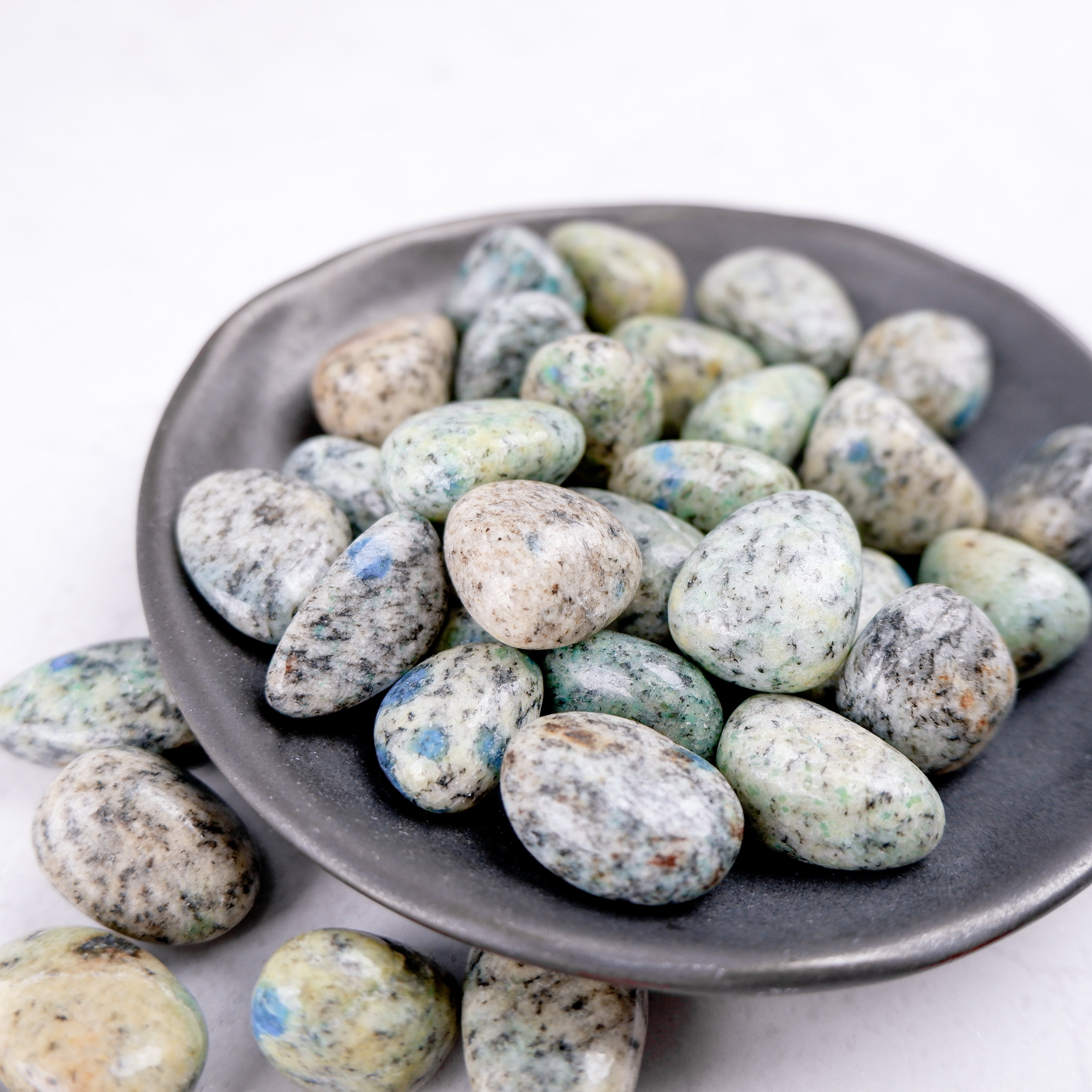 Noctis Studio K2 Tumble Stone displaying a polished, irregular-shaped mineral with vibrant blue and green hues.