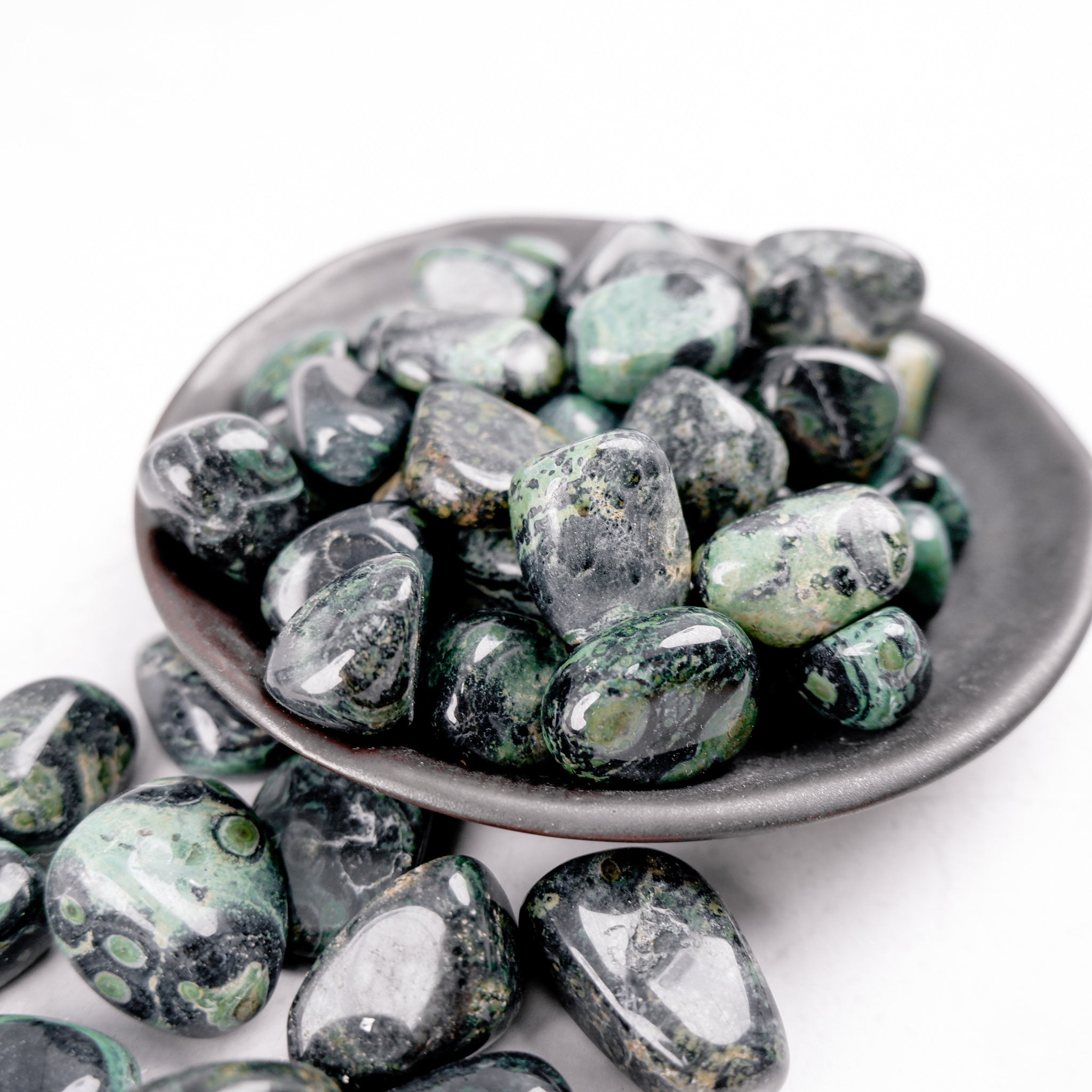Kambaba Jasper tumble stone from Noctis Studio, smooth polished mineral with swirling green and black patterns.