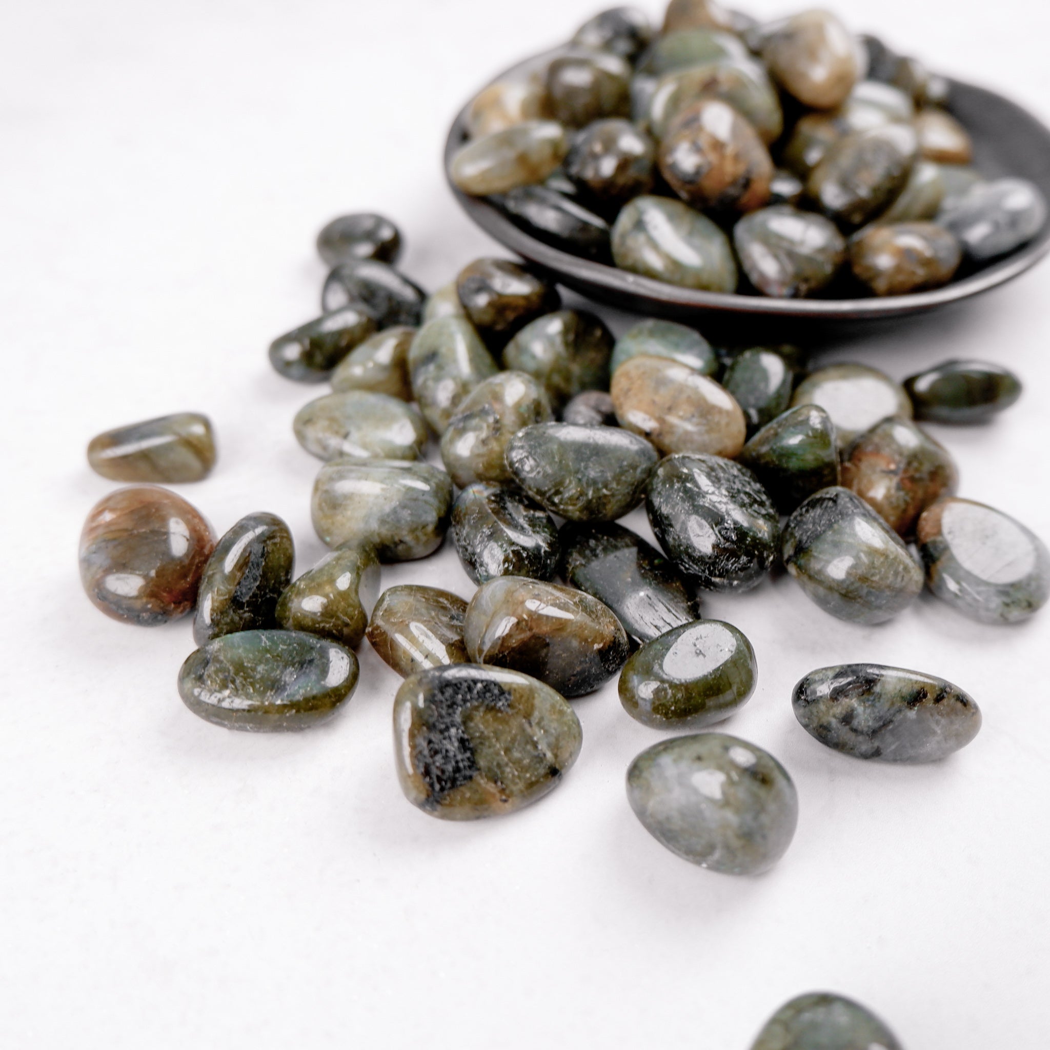 Labradorite tumble stone from Noctis Studio showing iridescent blue and green flashes on smooth, polished surface.