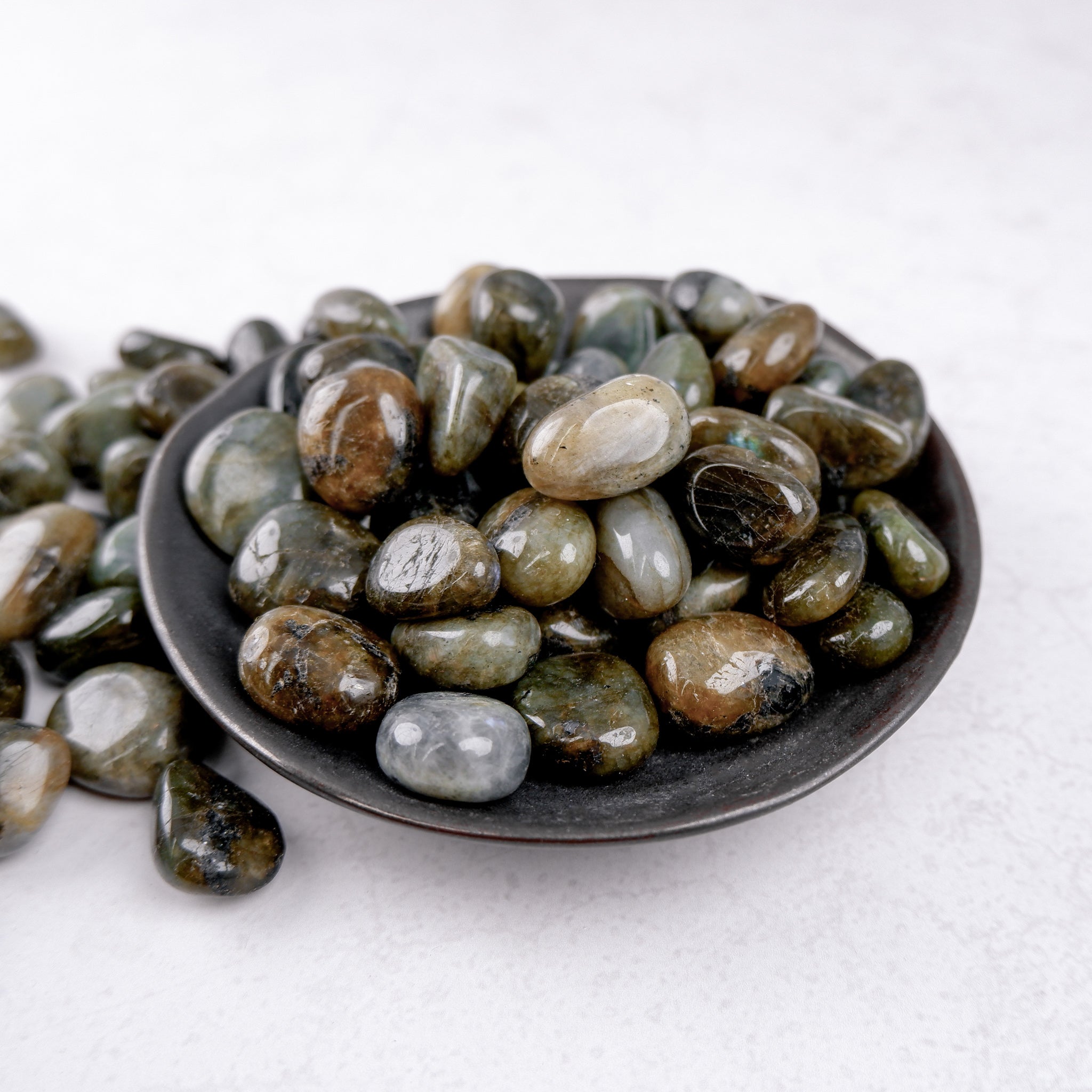 Labradorite tumble stone from Noctis Studio showing iridescent gray and blue hues, polished smooth gemstone for jewelry or collection.