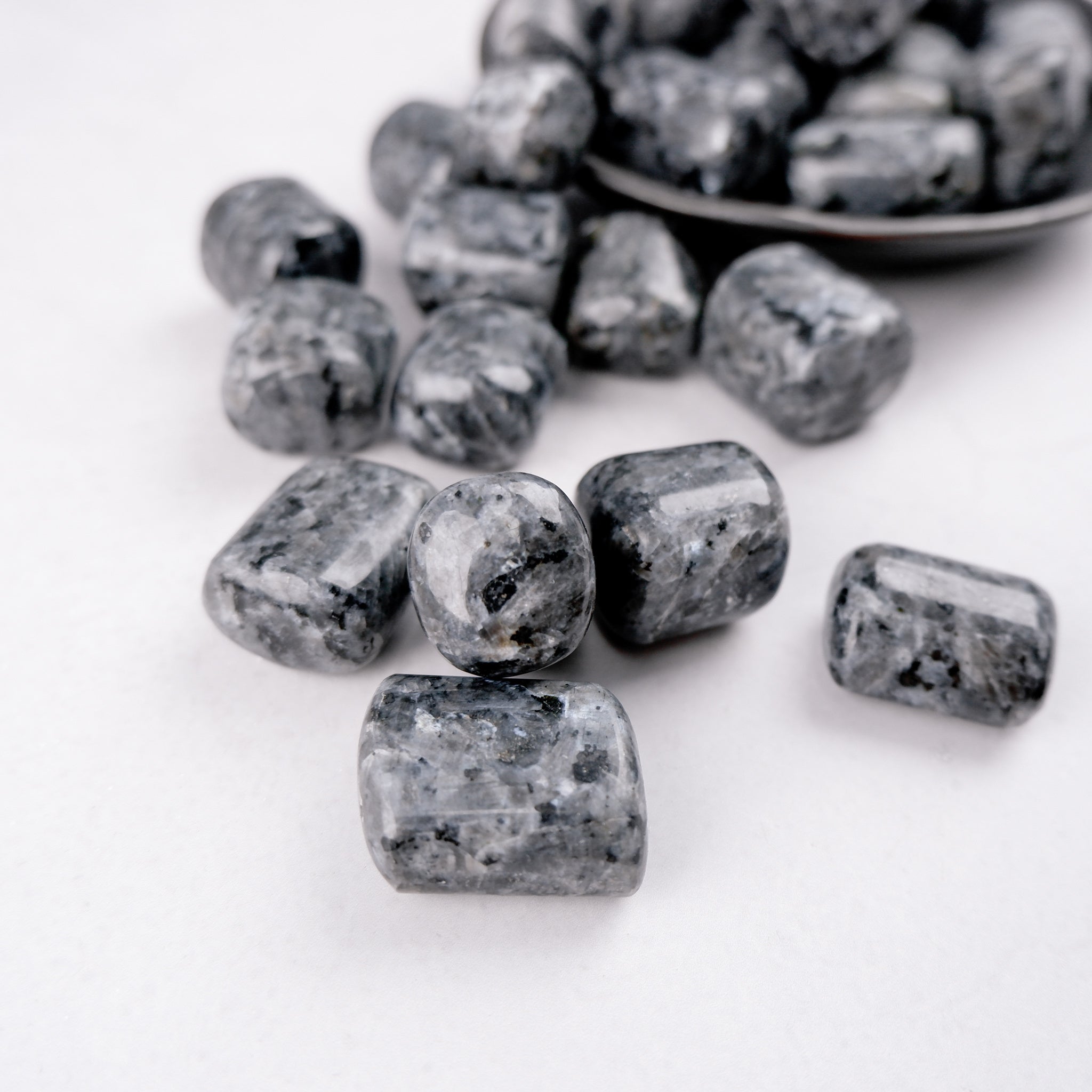 Larvikite tumble stone from Noctis Studio, polished gemstone with dark blue and black hues, showcasing unique natural patterns.
