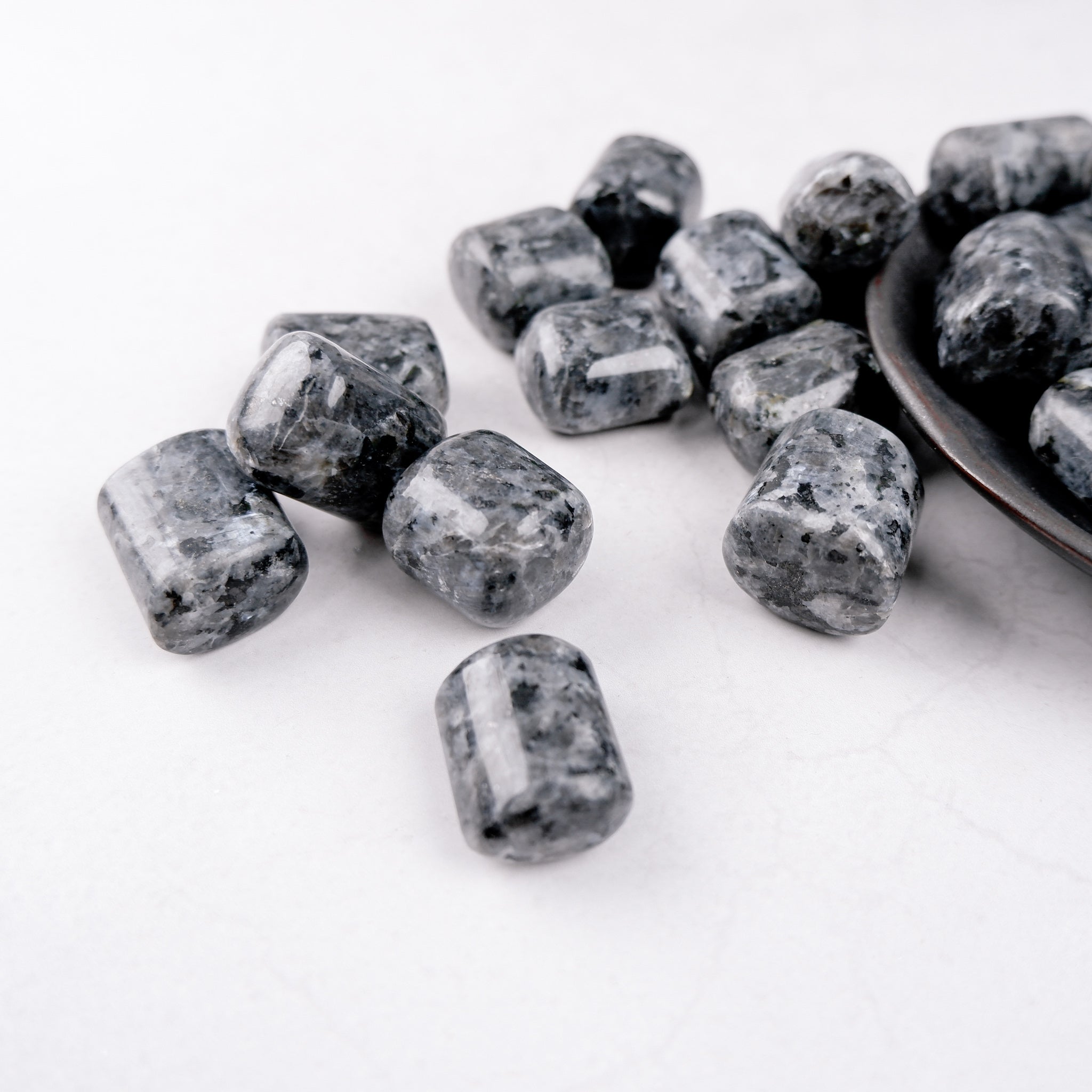 Larvikite tumble stone from Noctis Studio, smooth polished gemstone with dark blue and silver flecks, natural mineral texture.
