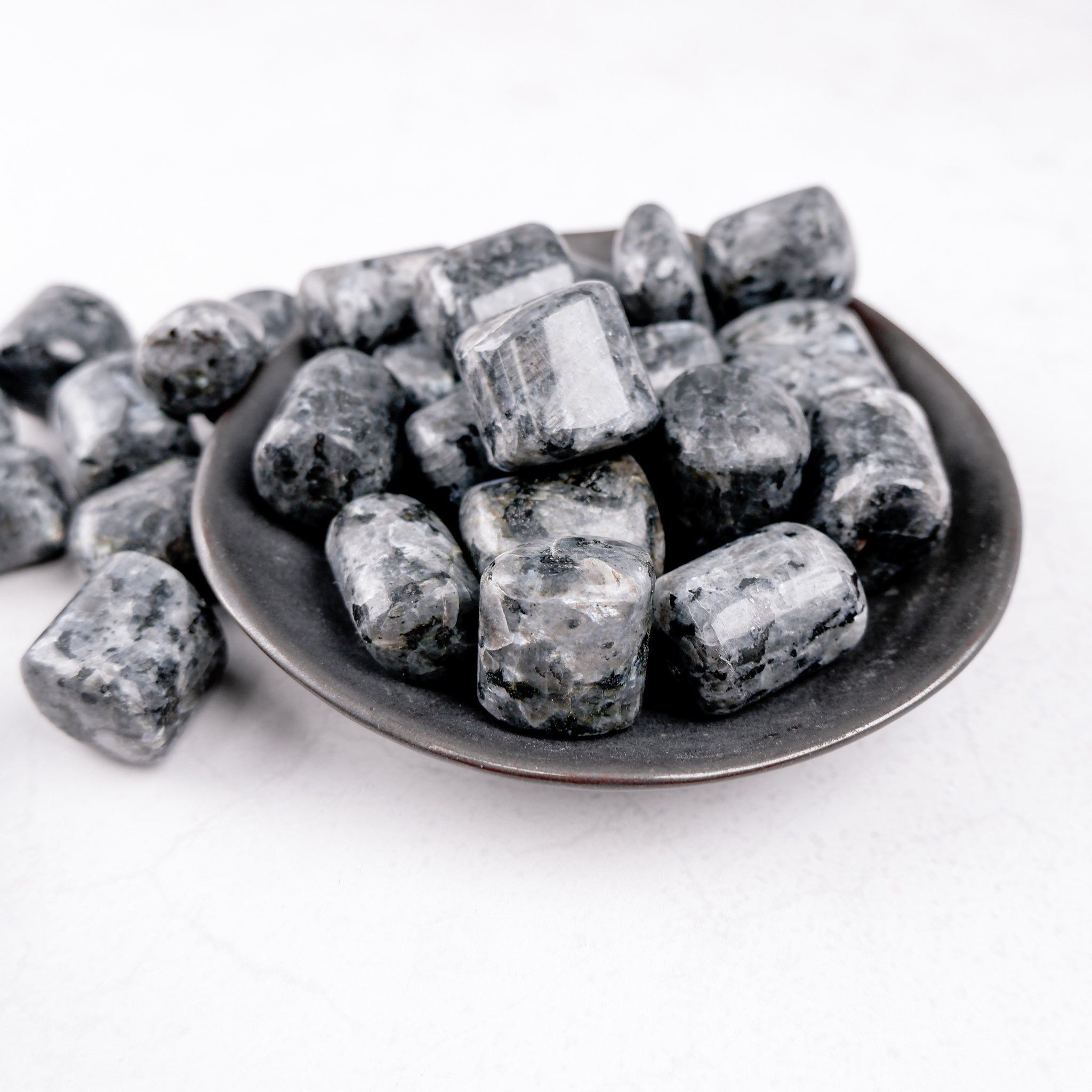 Larvikite tumble stone from Noctis Studio, showcasing polished dark blue-gray mineral with iridescent flashes.