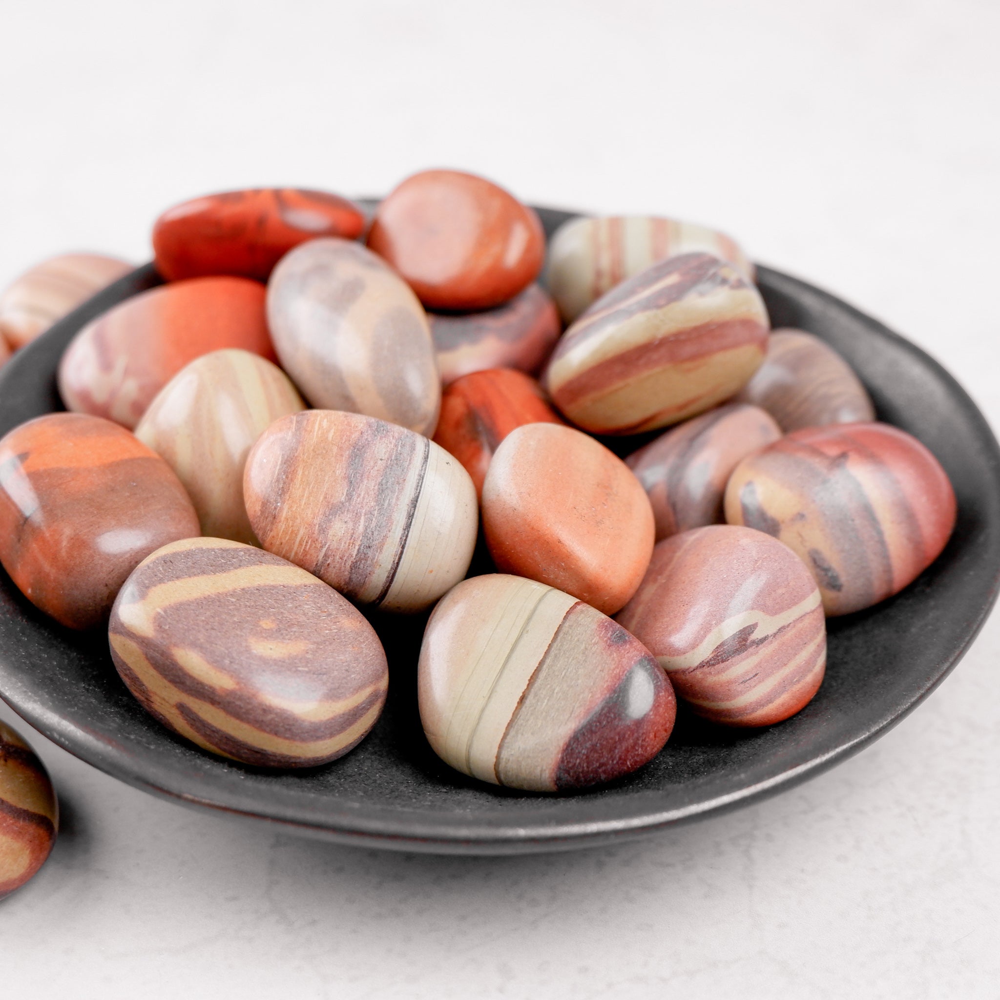 Noctis Studio Print Stone Tumble Stone with textured, polished surface in earthy tones, showcasing its smooth, rounded shape.