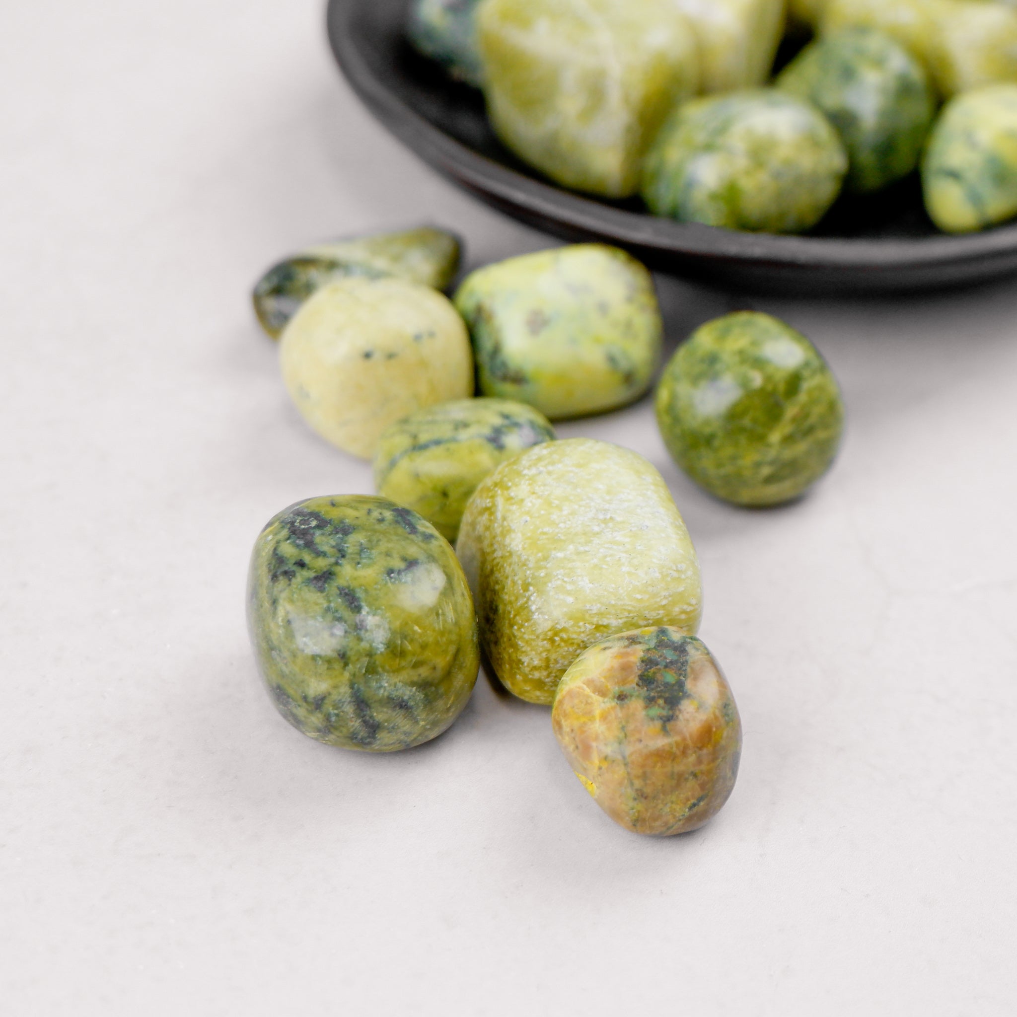 Serpentine tumble stone from Noctis Studio, showing smooth, polished green and black mineral with natural patterns.