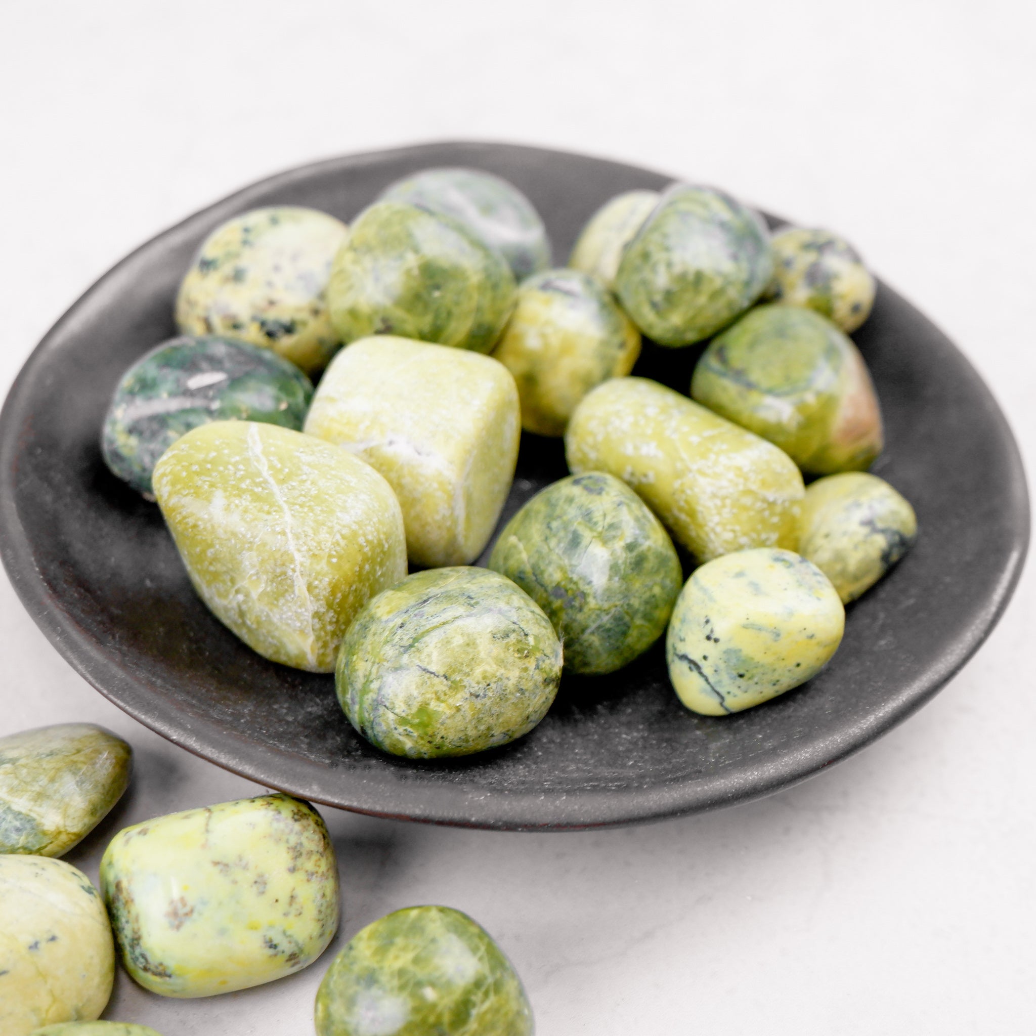 Serpentine tumble stone from Noctis Studio, showcasing a smooth polished green mineral with natural patterns and rich coloration.