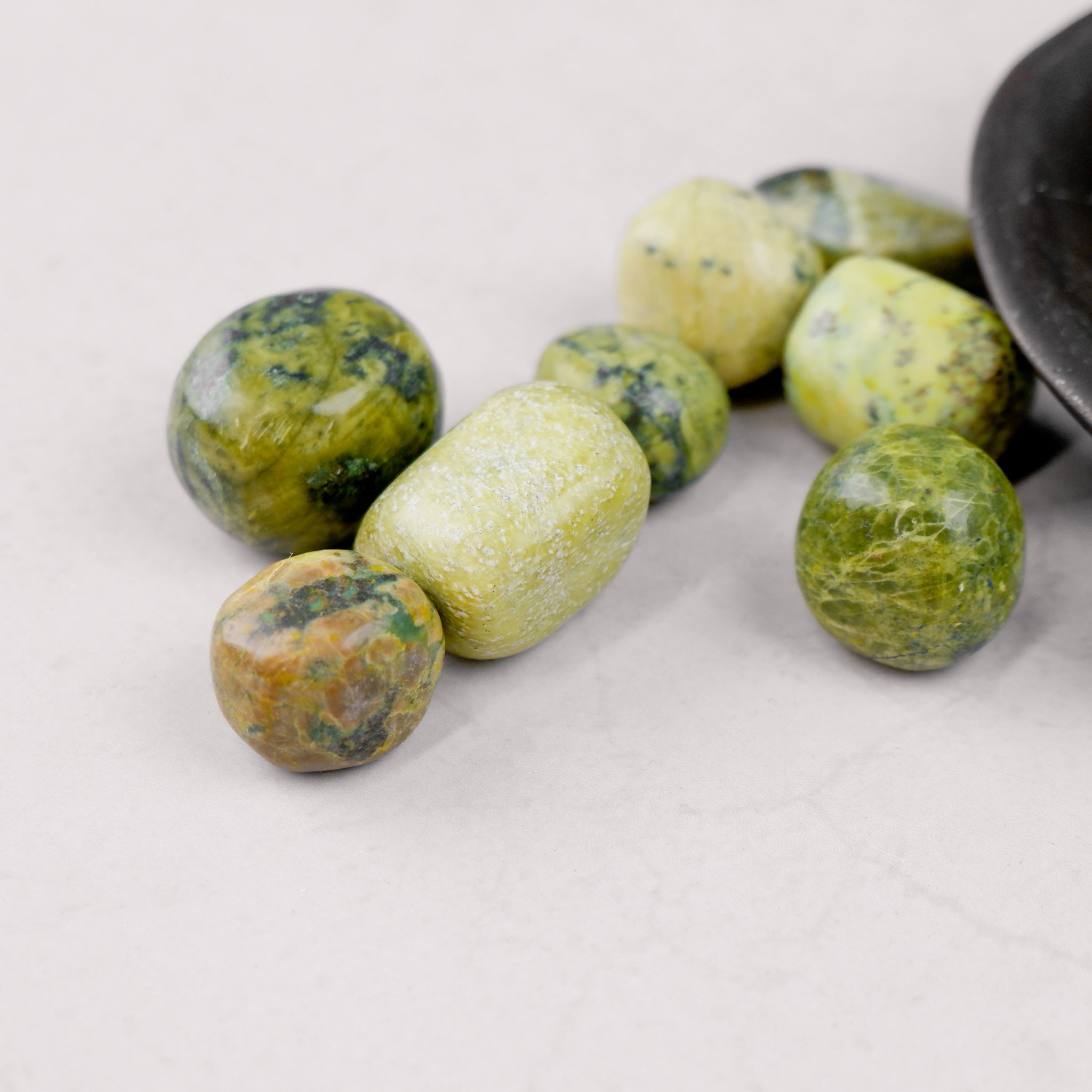 Noctis Studio serpentine tumble stone showing smooth, green mineral with natural patterns and polished surface.