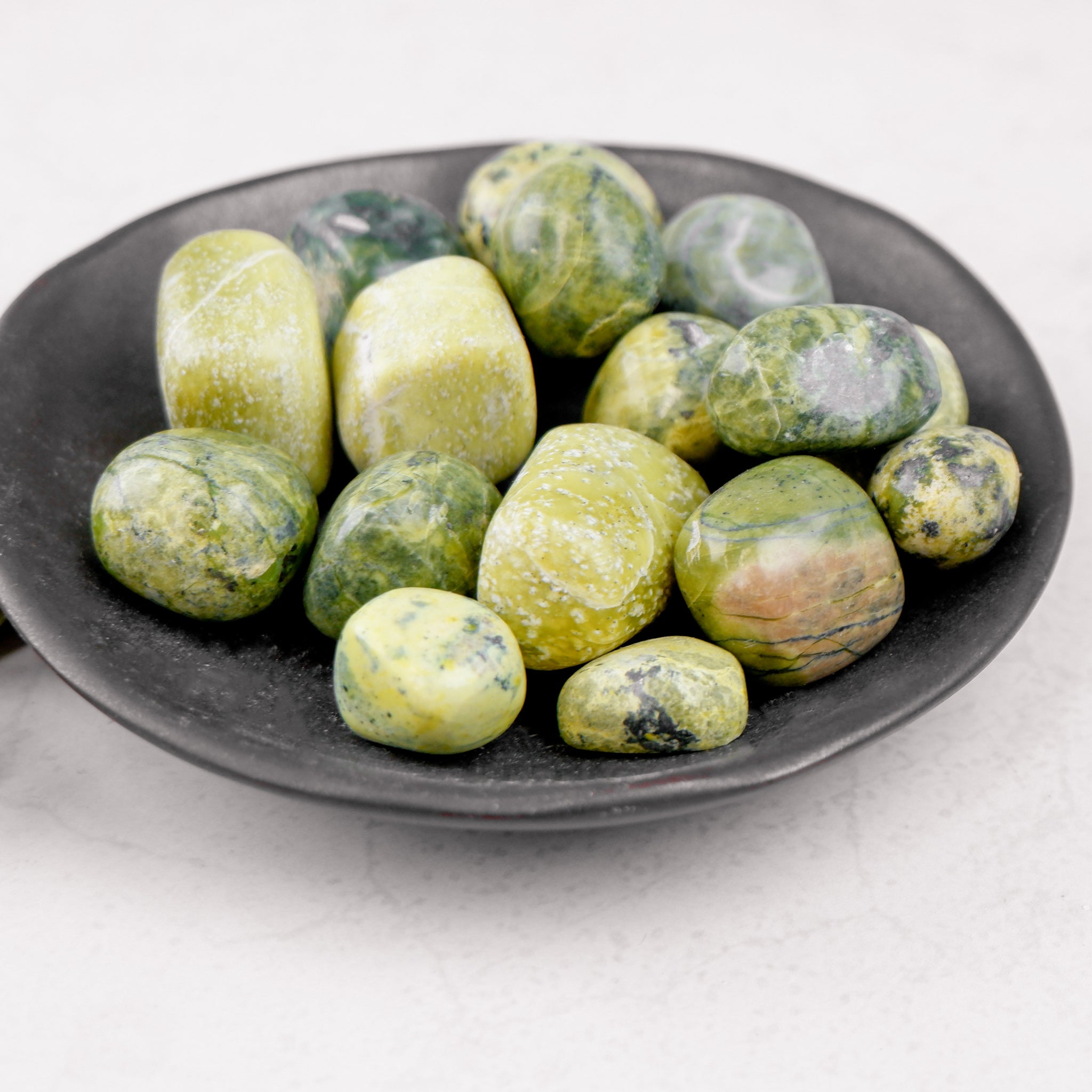 Serpentine tumble stone from Noctis Studio showing smooth, polished green gemstone with natural patterns and rounded shape.
