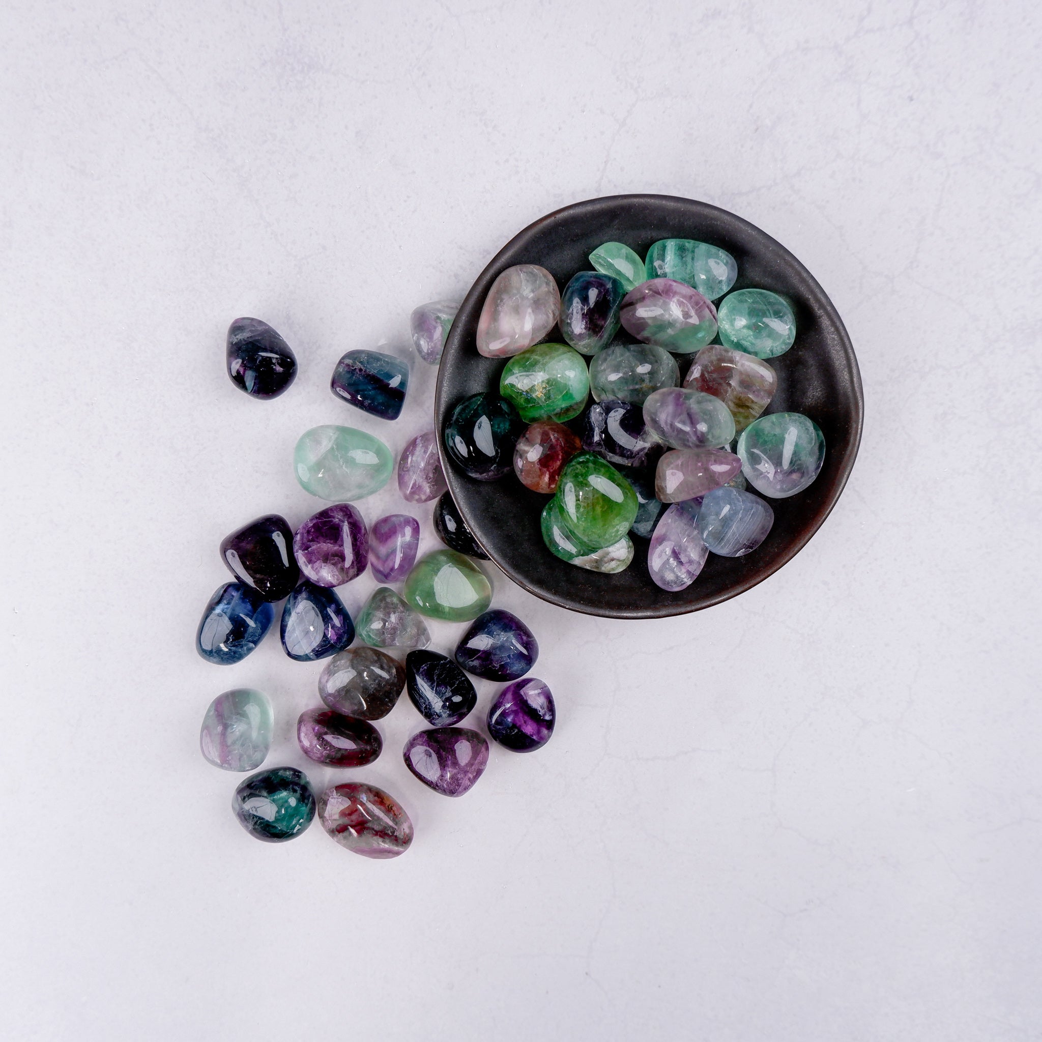 Noctis Studio fluorite tumble stone displaying vibrant green and purple hues with a polished, smooth surface.