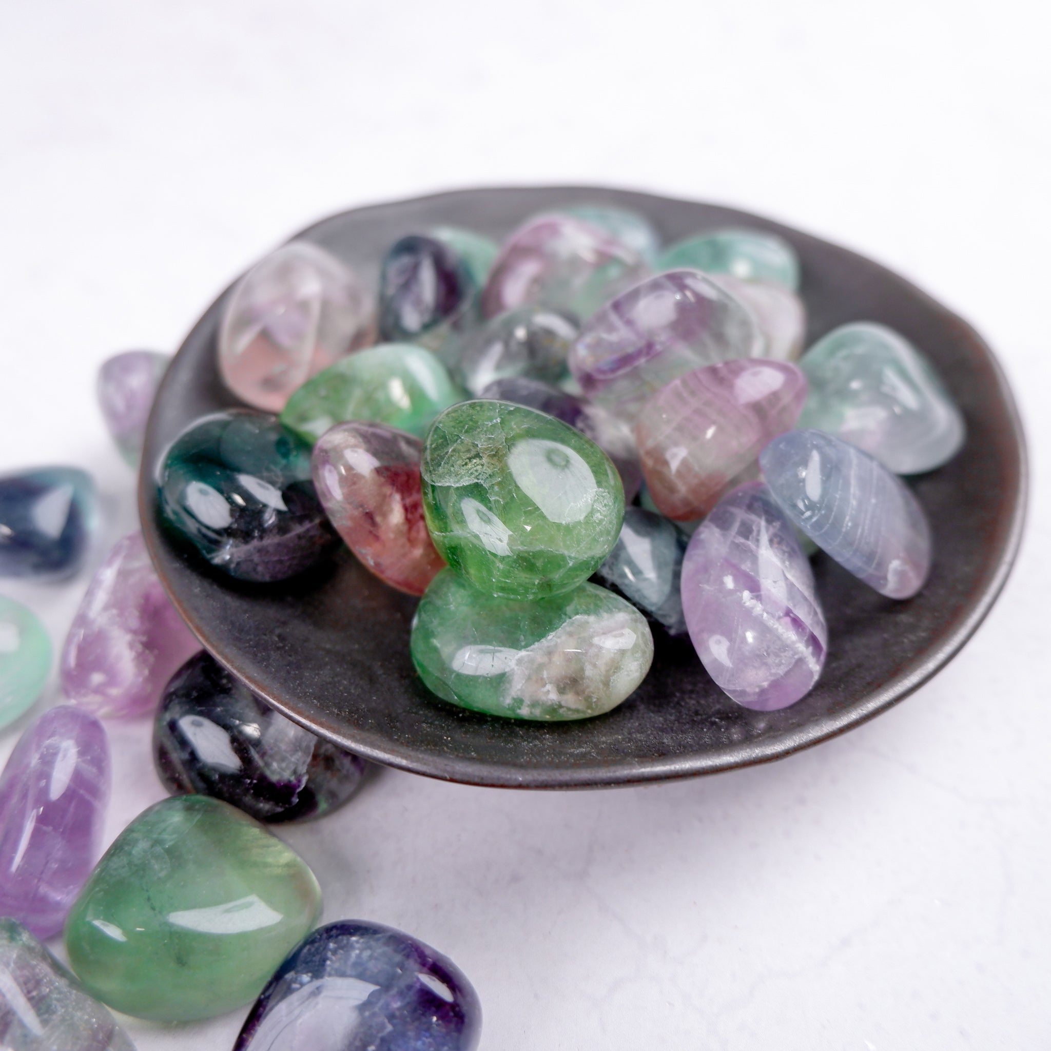 Noctis Studio fluorite tumble stone showing vibrant green and purple mineral formations on a smooth polished surface.