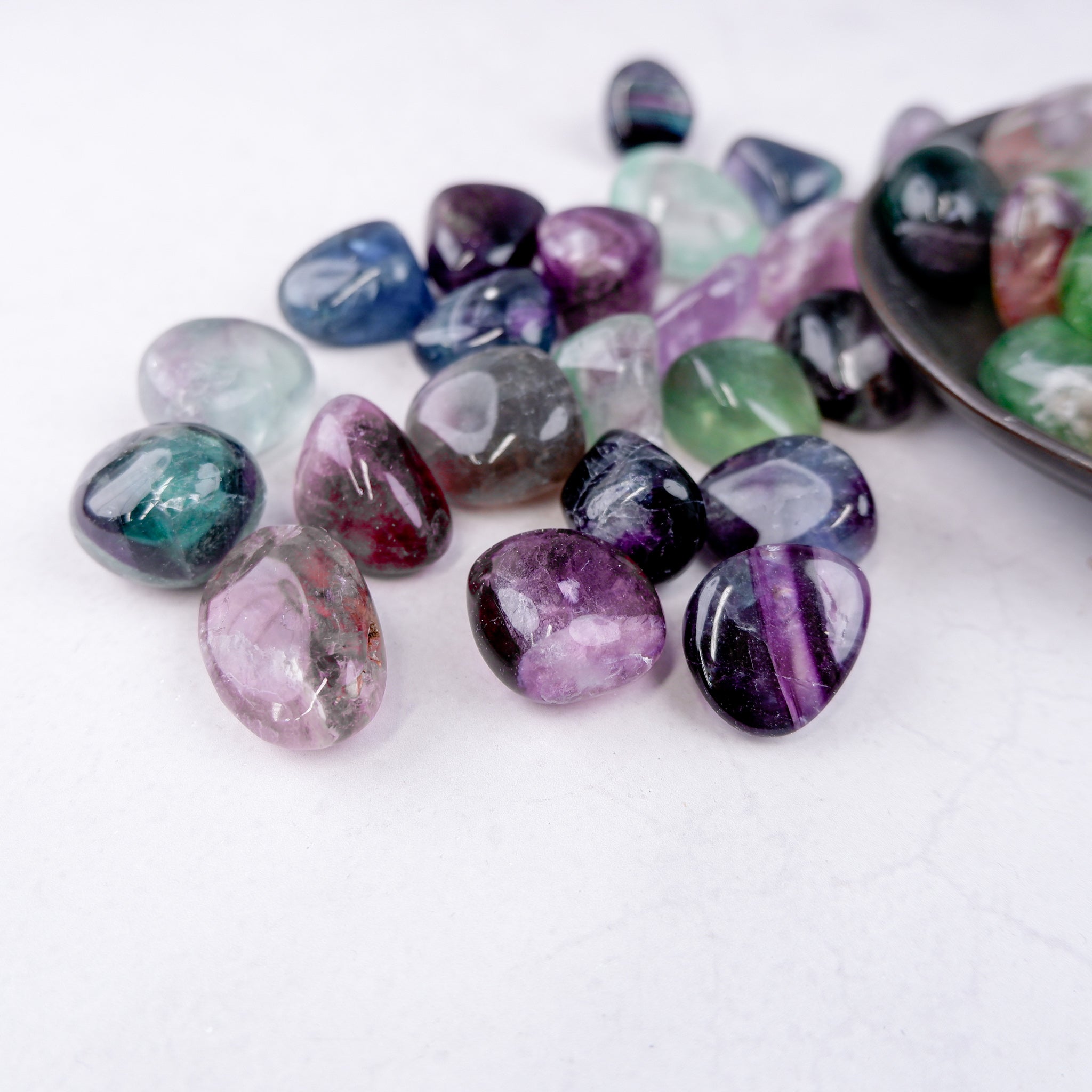 Noctis Studio fluorite tumble stone showcasing vibrant purple and green mineral patterns on a smooth, polished surface.