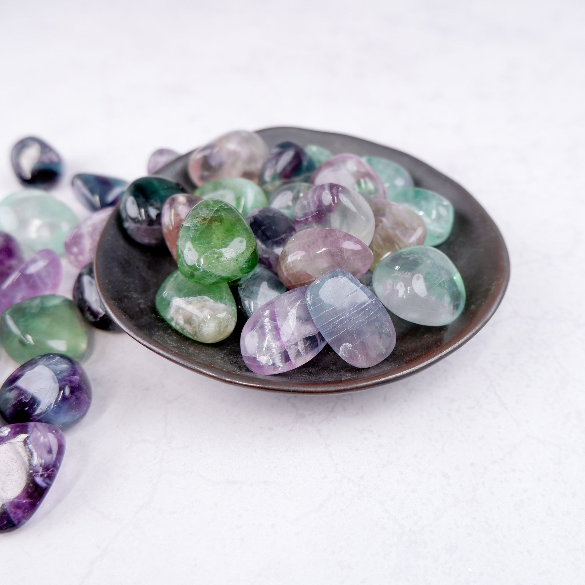 Noctis Studio fluorite tumble stone with vibrant green and purple hues, smooth polished surface, and natural mineral patterns.