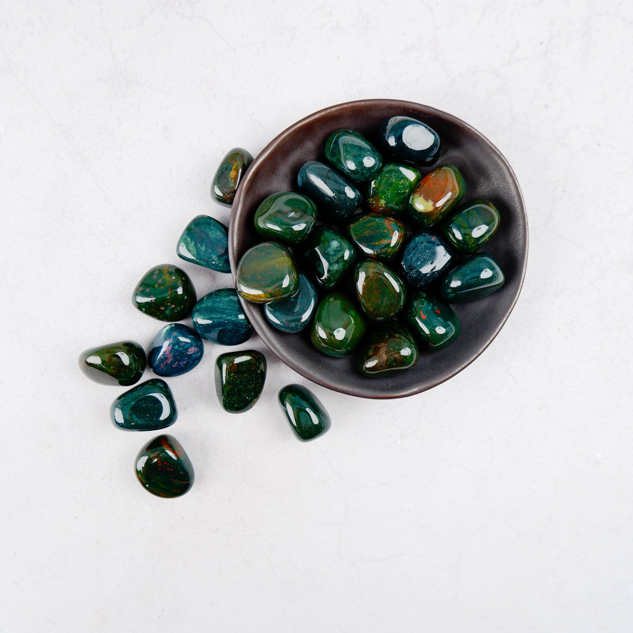 Bloodstone tumble stone from Noctis Studio, showing a polished green and red gemstone with natural patterns and smooth rounded edges.