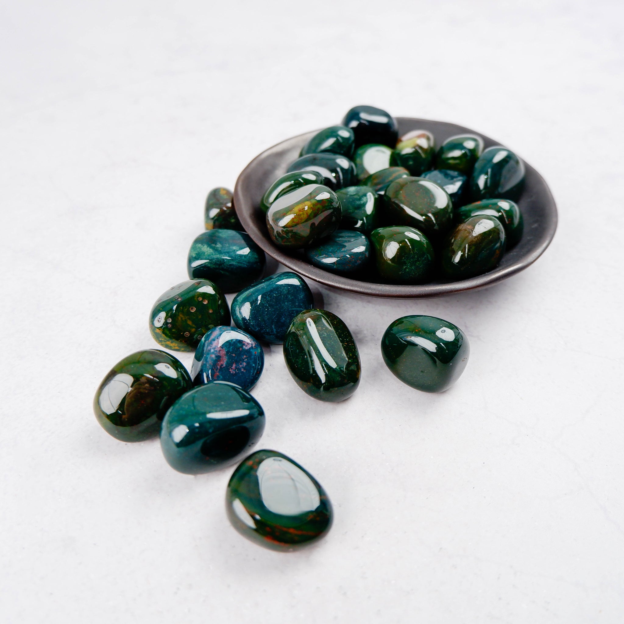 Bloodstone tumble stone from Noctis Studio, showing a polished green and red gemstone with natural patterns and smooth rounded edges.