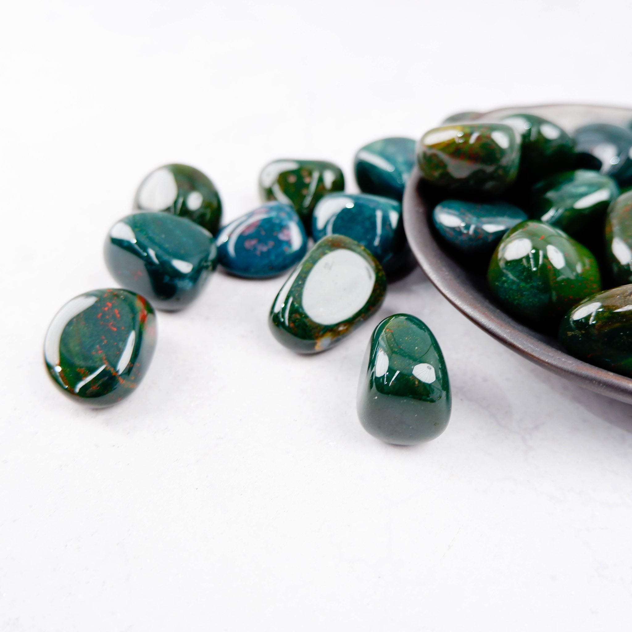 Bloodstone tumble stone from Noctis Studio, polished mineral with deep green and red hues, displayed on a neutral background.