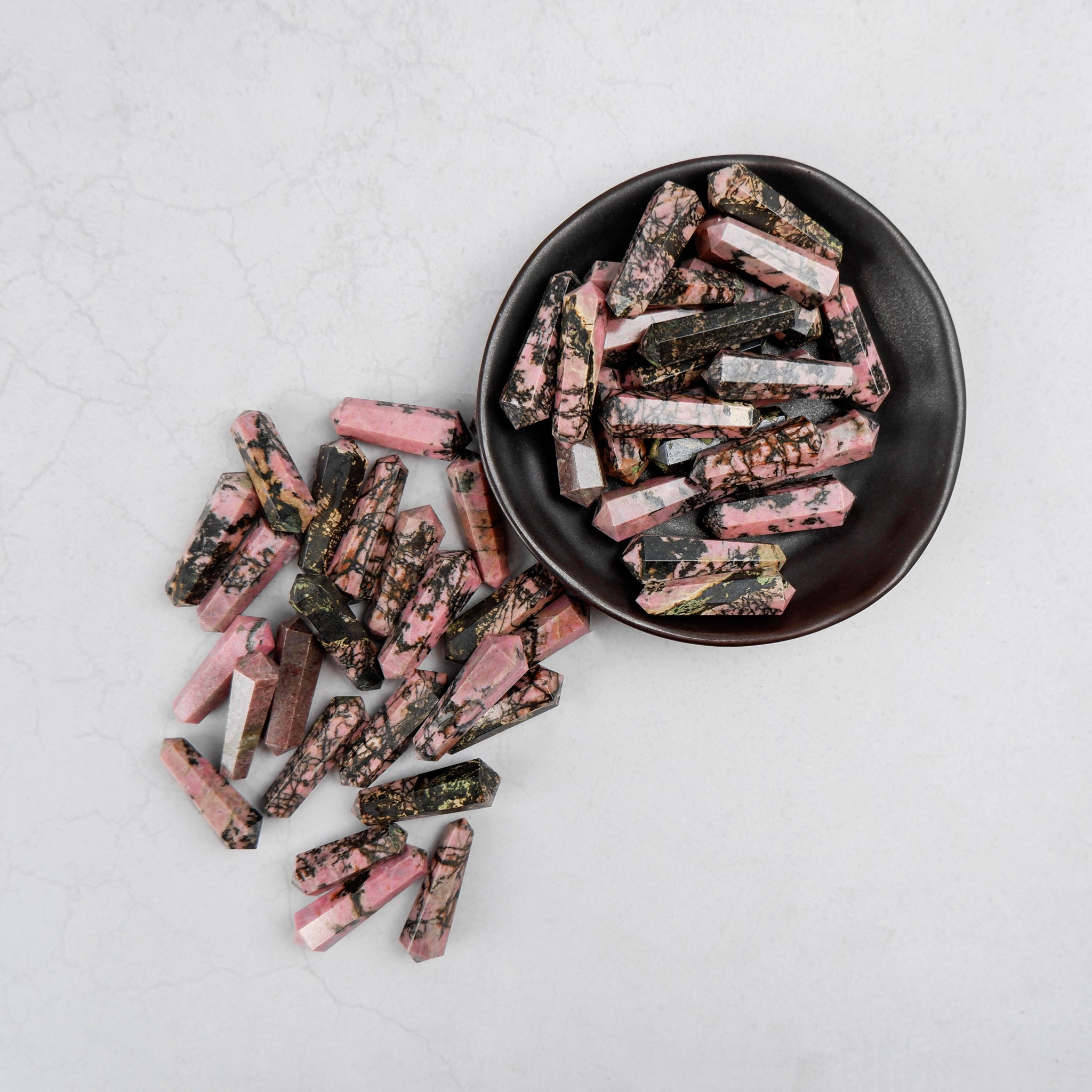 Rhodonite double gridding point from Noctis Studio, showing a polished pink and black gemstone tool with pointed ends.