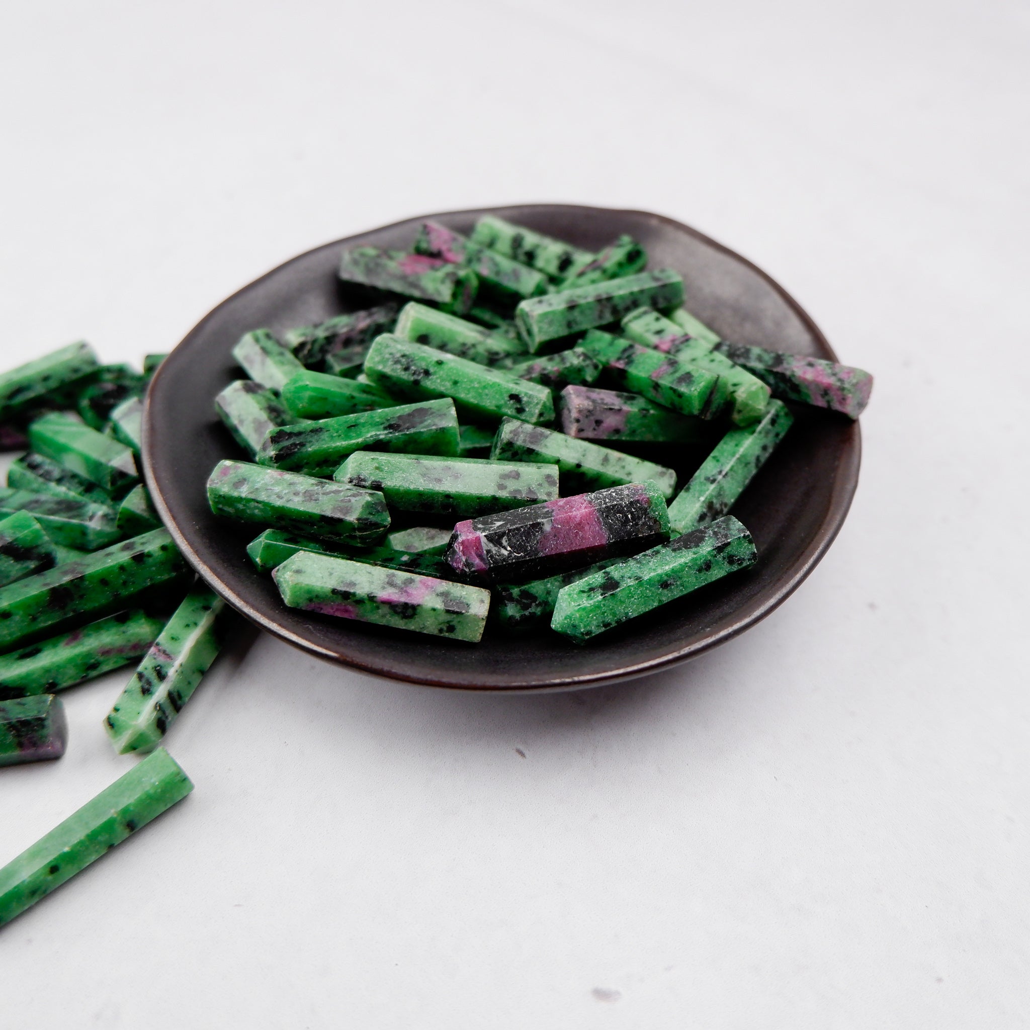 Ruby in Zoisite single gridding point from Noctis Studio, showcasing a polished gemstone with vibrant red and green colors.