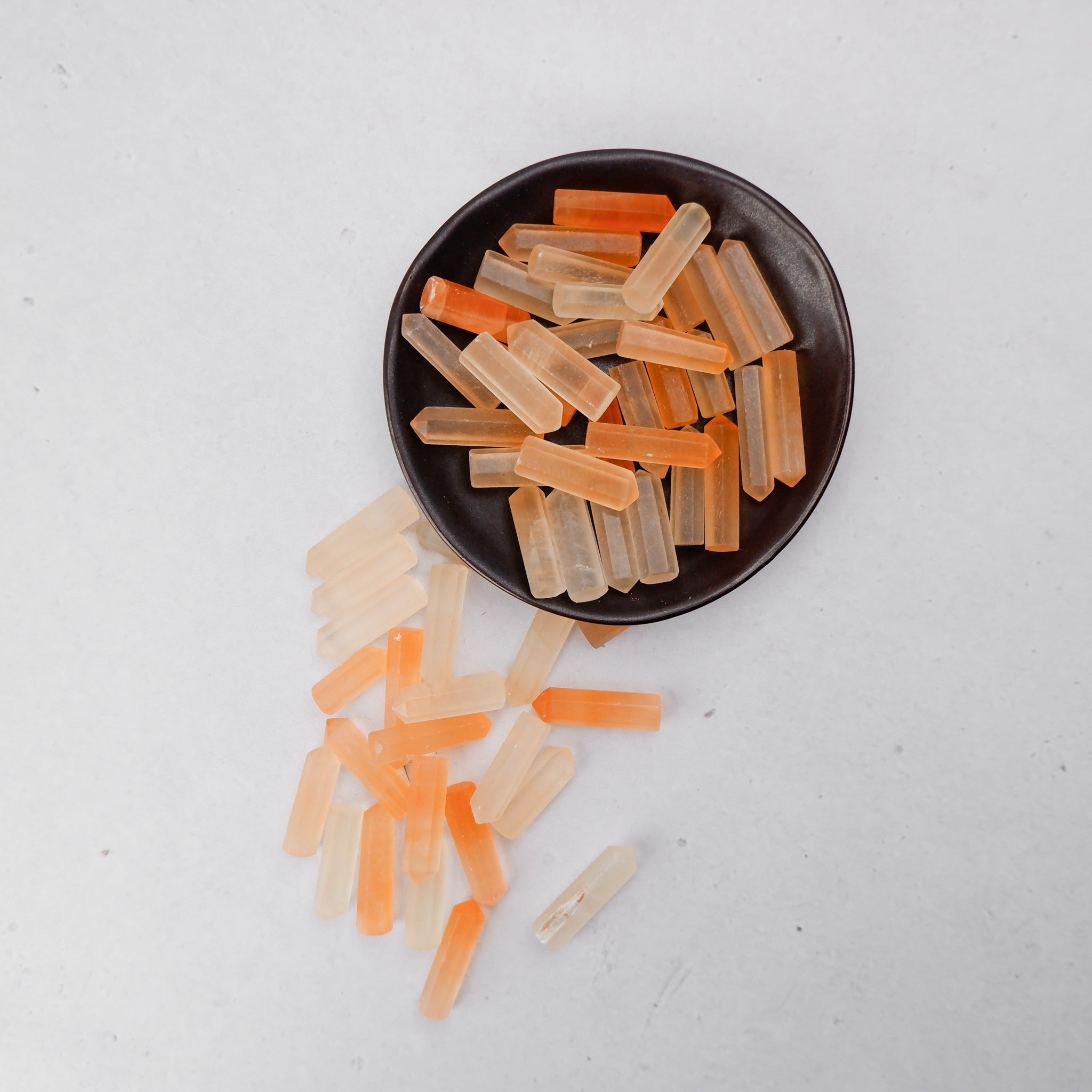 Orange Selenite single gridding point from Noctis Studio, showing a smooth, pointed crystal with vibrant orange color and natural crystal formations.