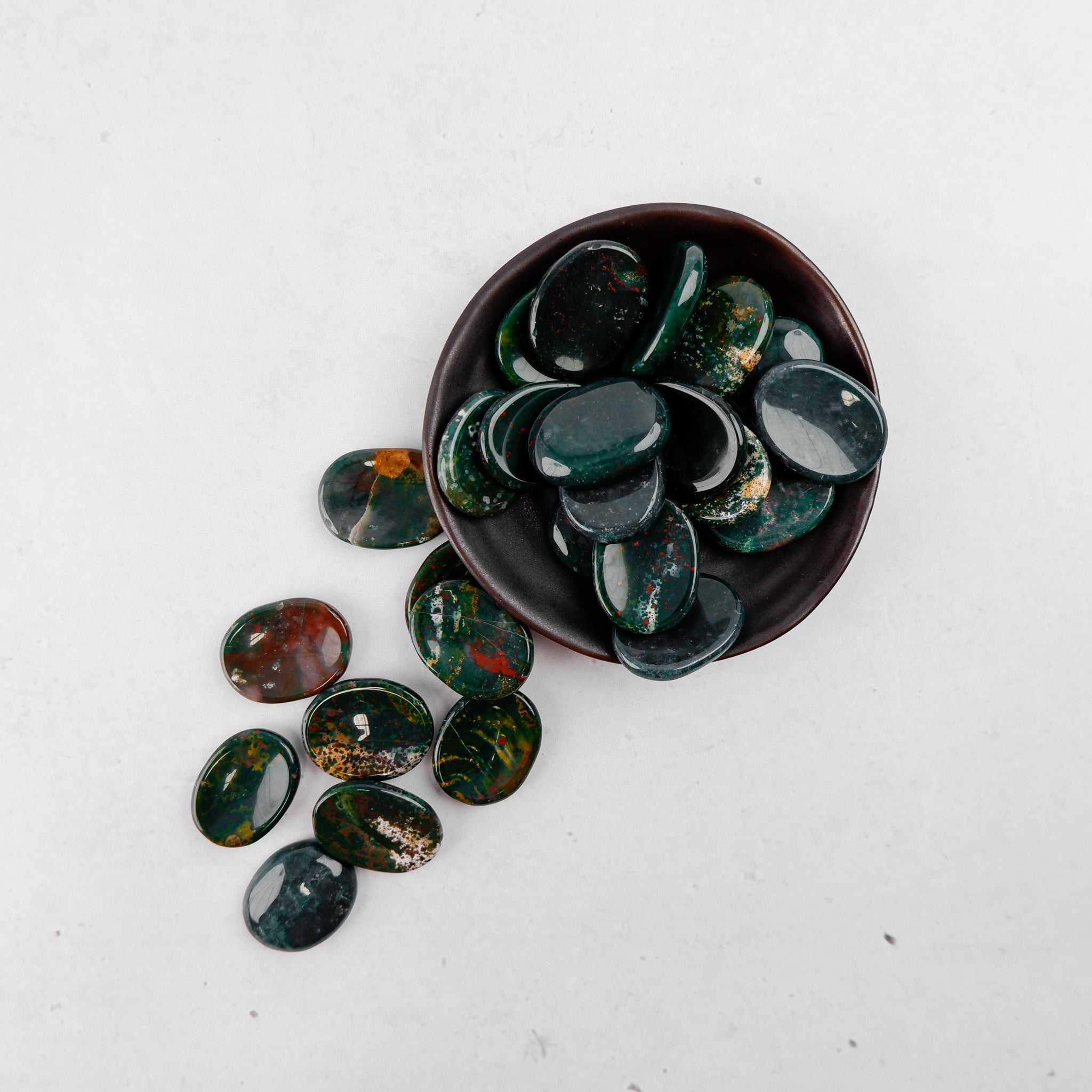 Bloodstone worry stone by Noctis Studio, smooth polished gemstone for stress relief and meditation, with deep green and red hues.