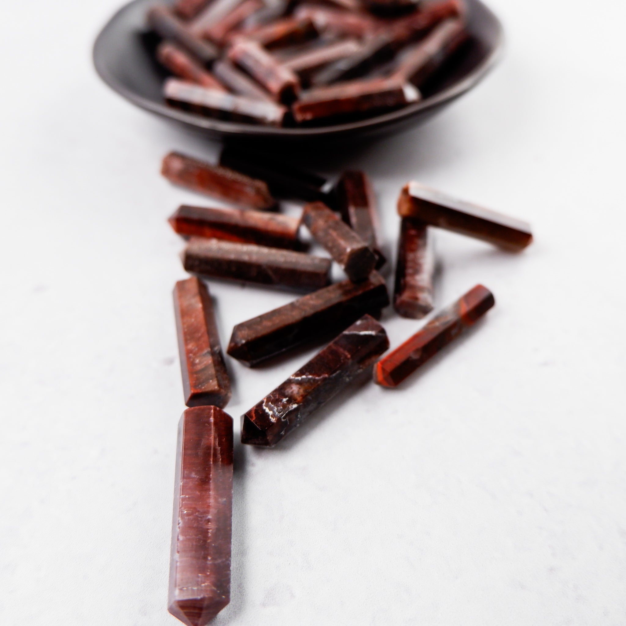 Red Tigers Eye single gridding point from Noctis Studio, showing a polished, pointed gemstone with rich red and brown hues.