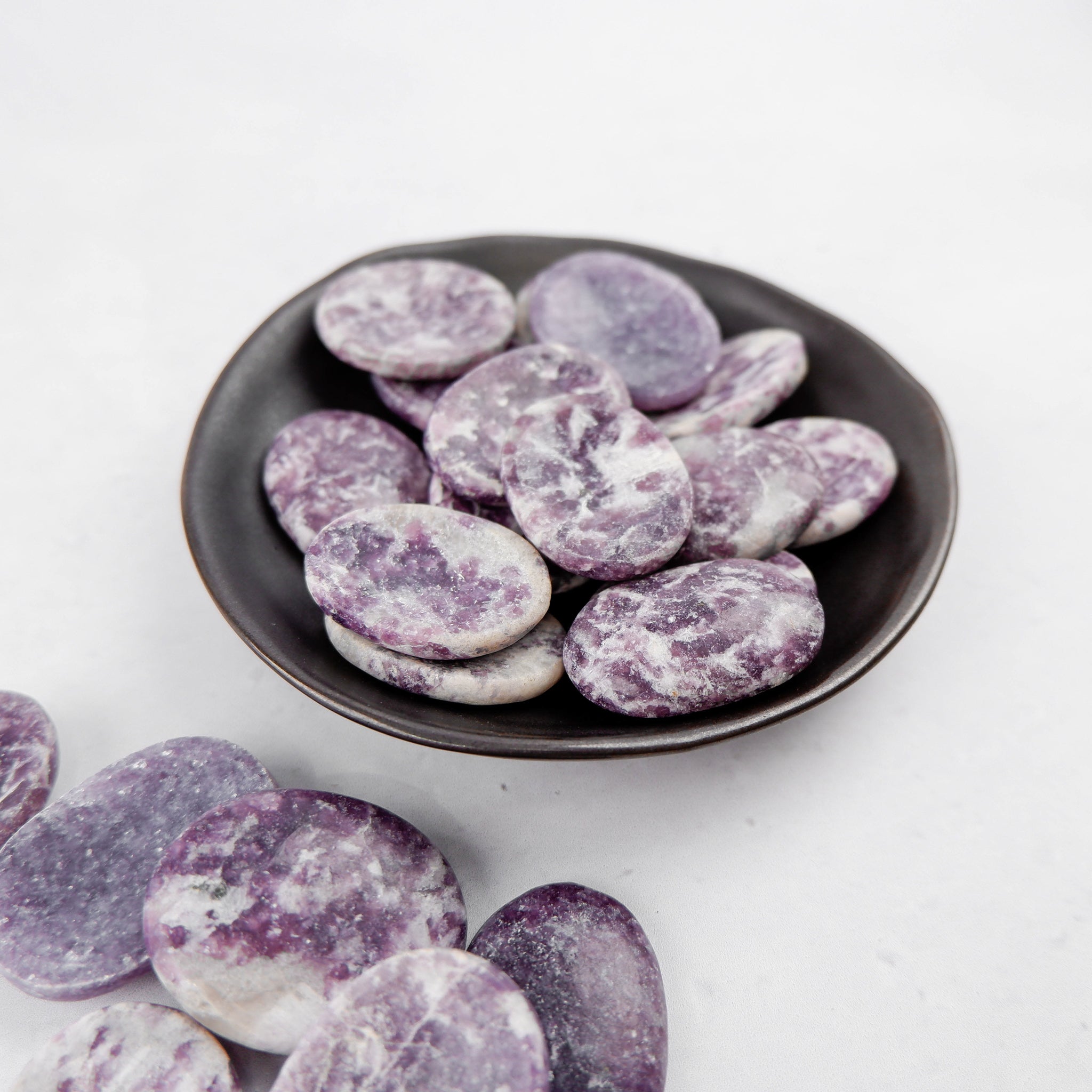 Lepidolite worry stone from Noctis Studio showing smooth, polished lavender-colored gemstone for stress relief and meditation.