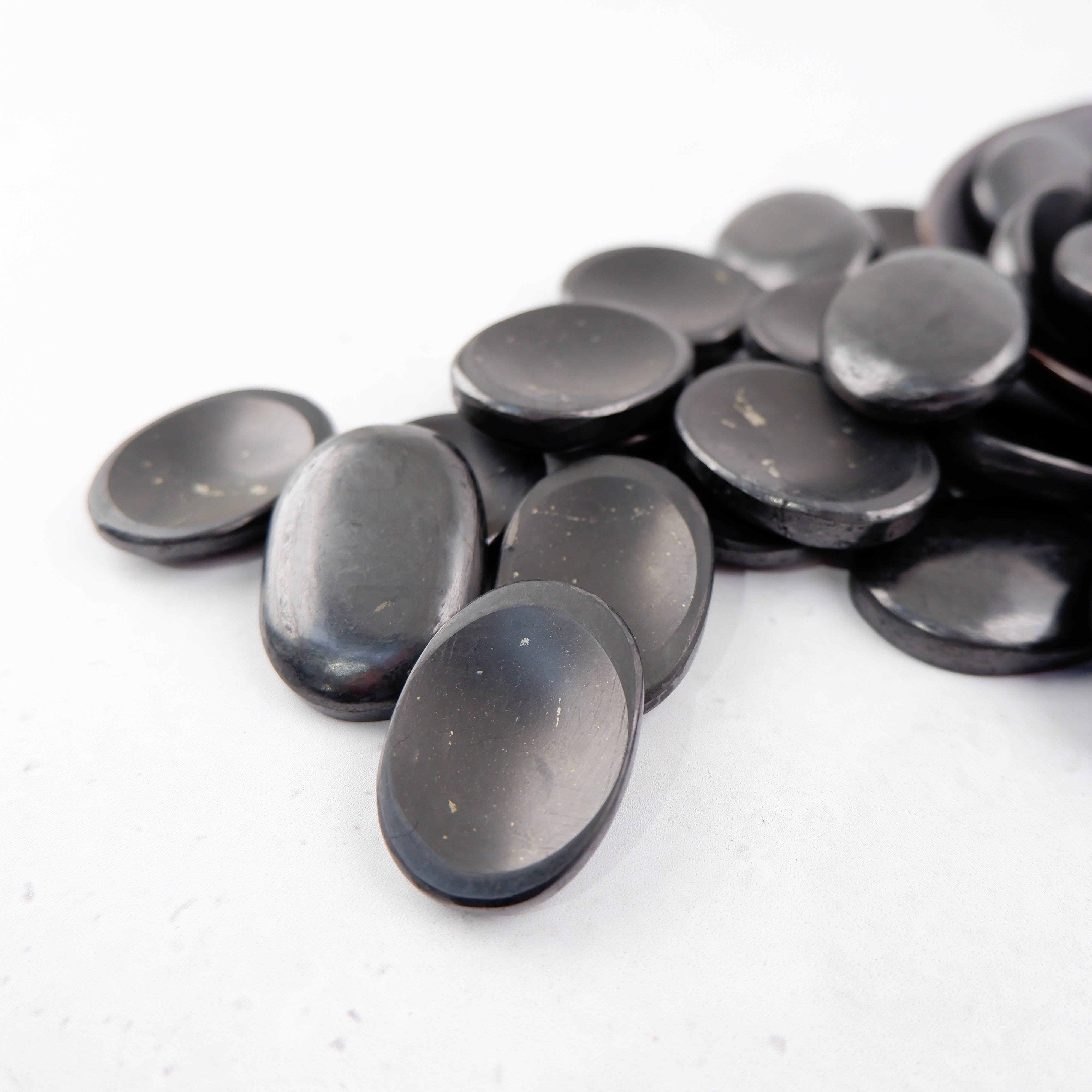Shungite worry stone from Noctis Studio, smooth black gemstone for stress relief and meditation, shown in close-up.