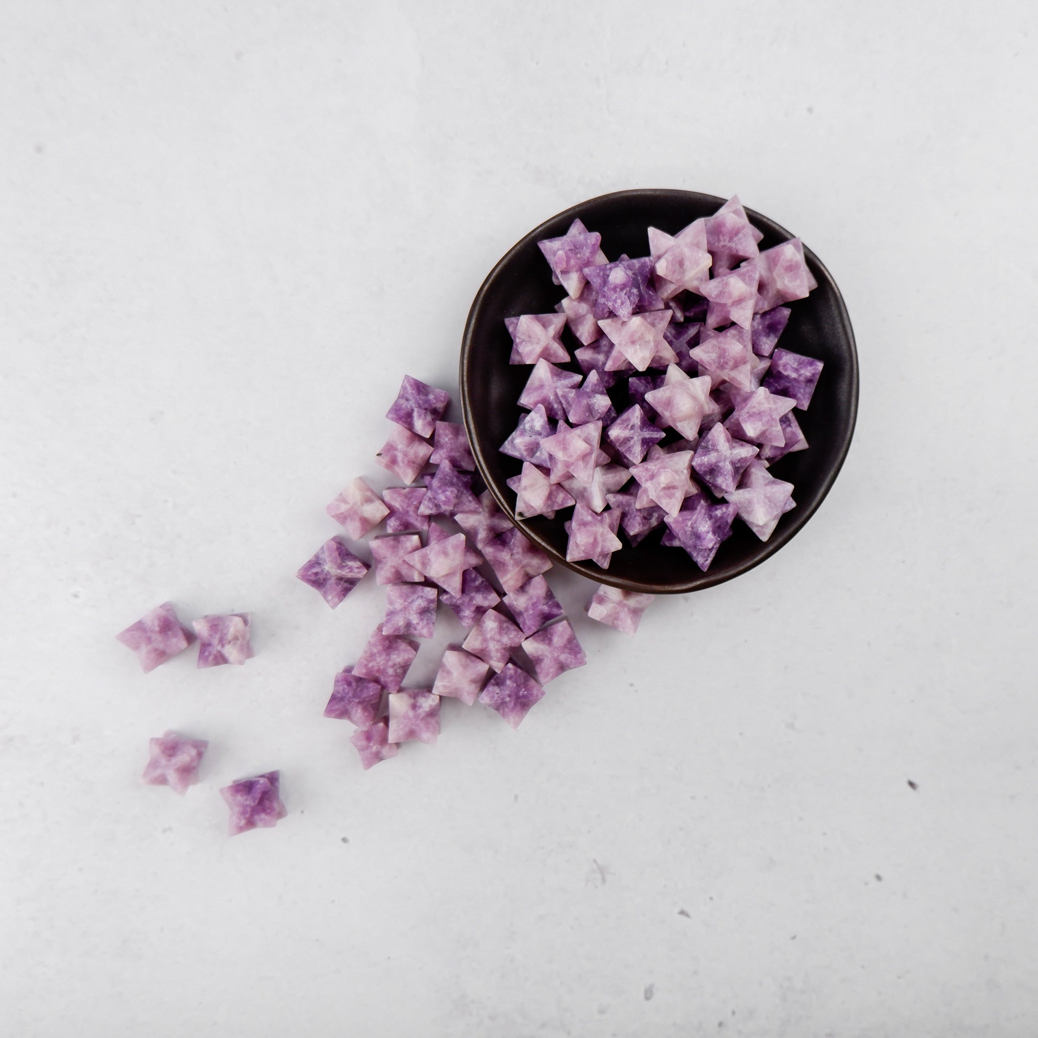 Lepidolite star crystal from Noctis Studio with purple and pink hues, polished to a smooth, star-shaped form.